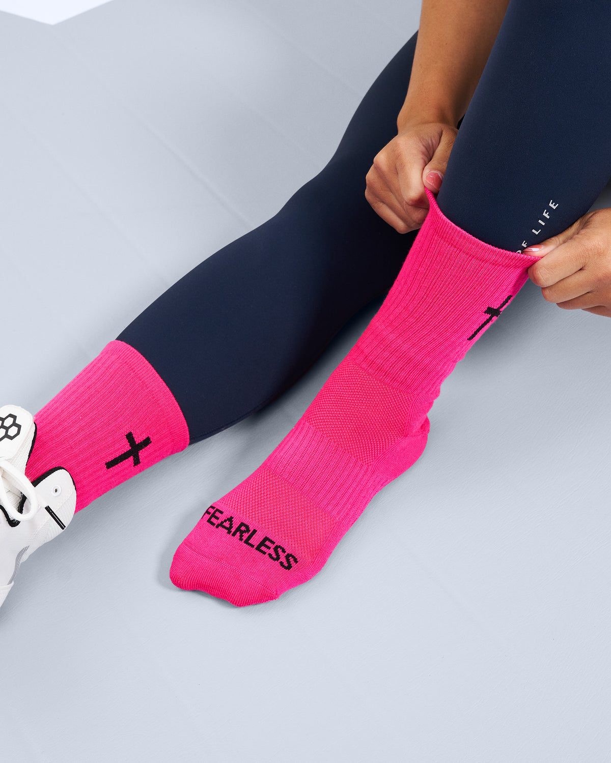Person wearing pink socks with 'FEARLESS' text on a light gray background
