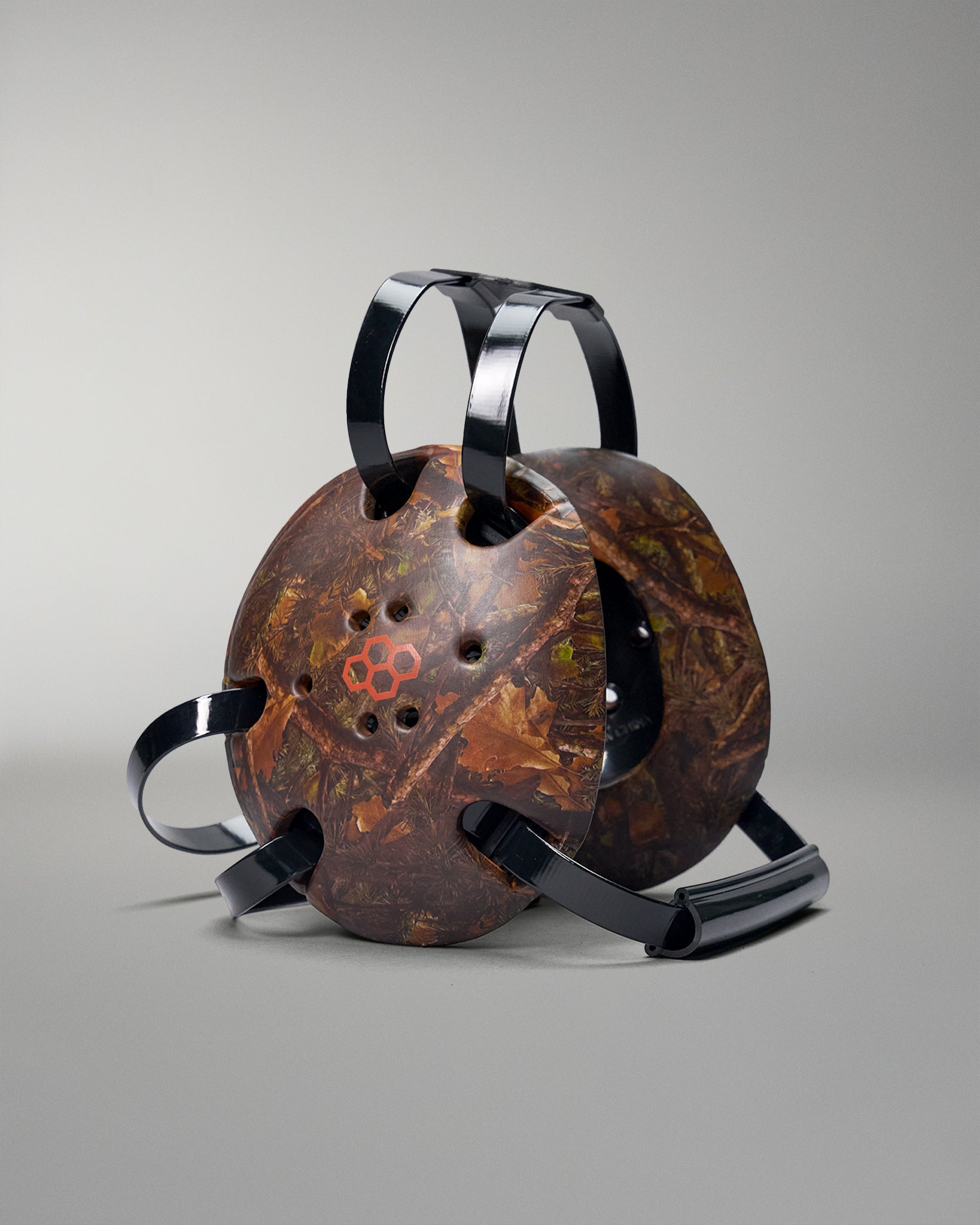 Rustic camo headgear with black handles on a gray background