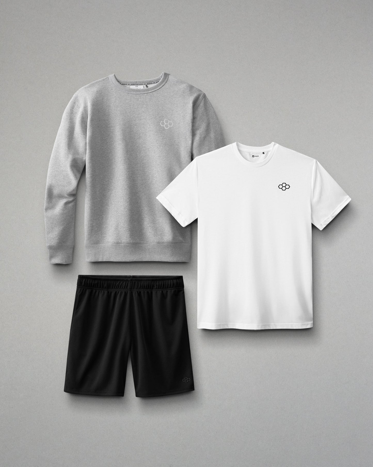 Gray sweatshirt, white t-shirt, and black shorts on a gray background