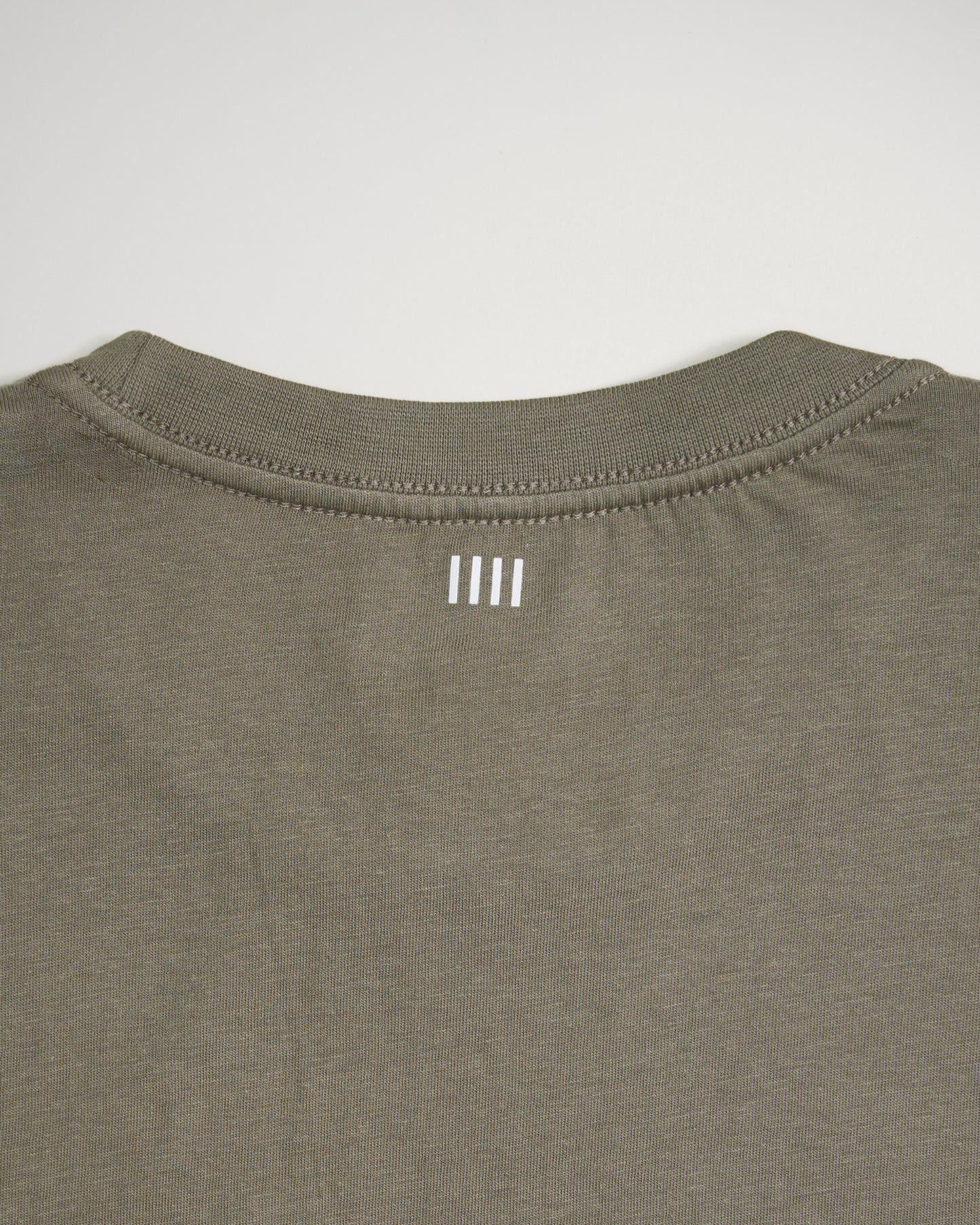 A close-up view of the back neckline of an olive green shirt featuring three vertical white lines as a design element
