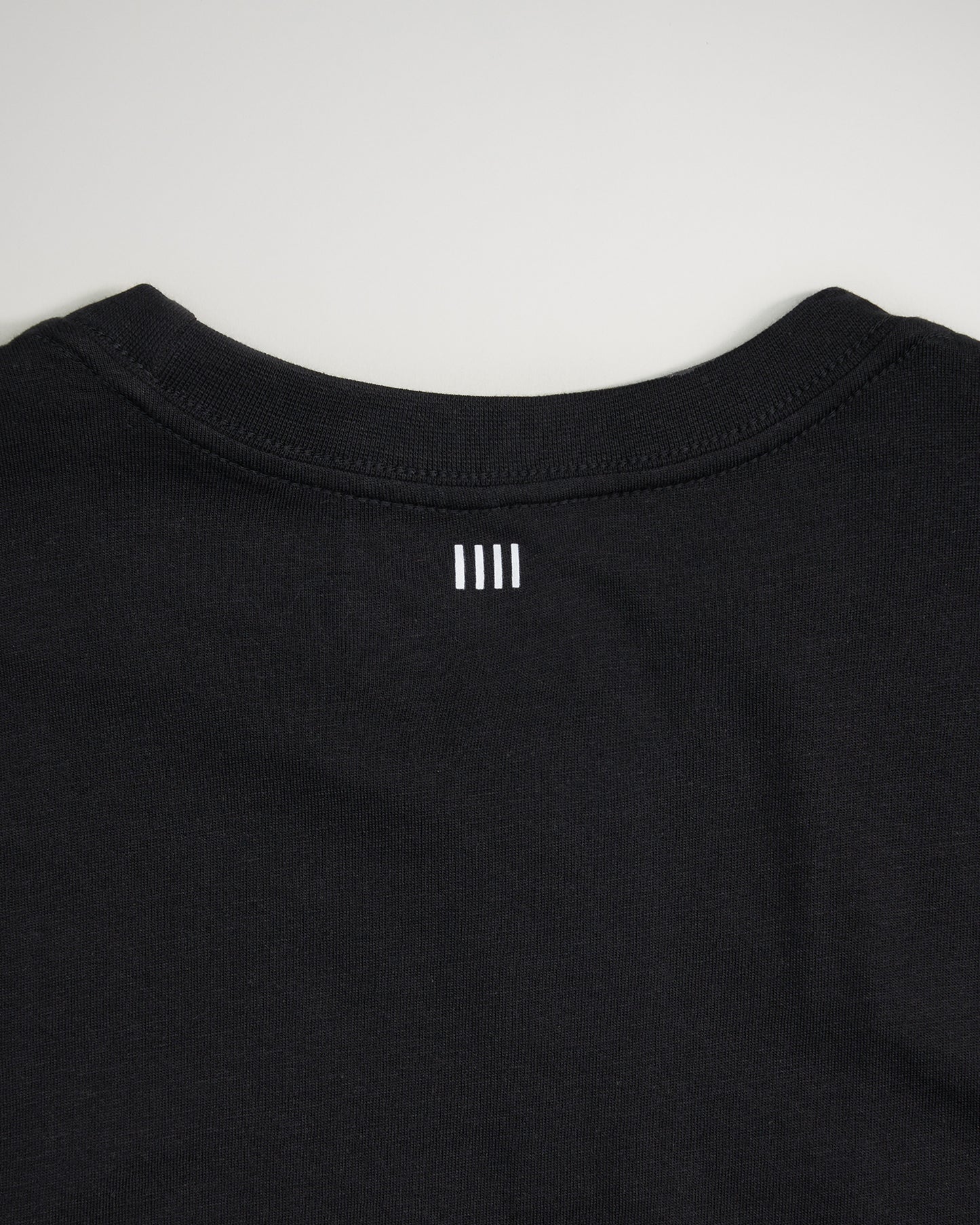 A close-up view of the back neckline of a black T-shirt featuring two white horizontal stripes and a minimalistic design