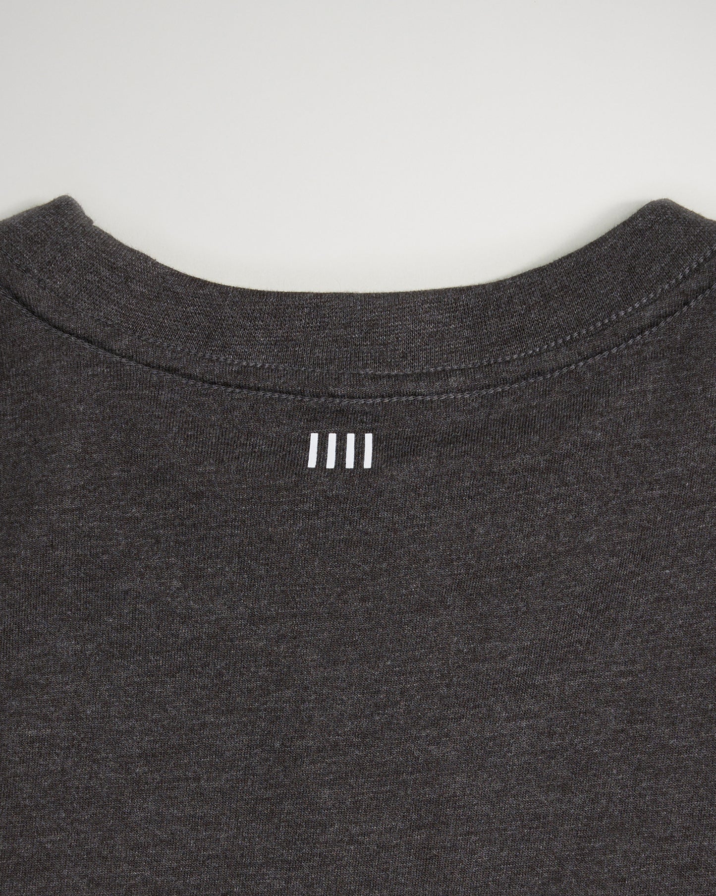 This image showcases the back neckline of a dark gray t-shirt featuring a subtle white logo design