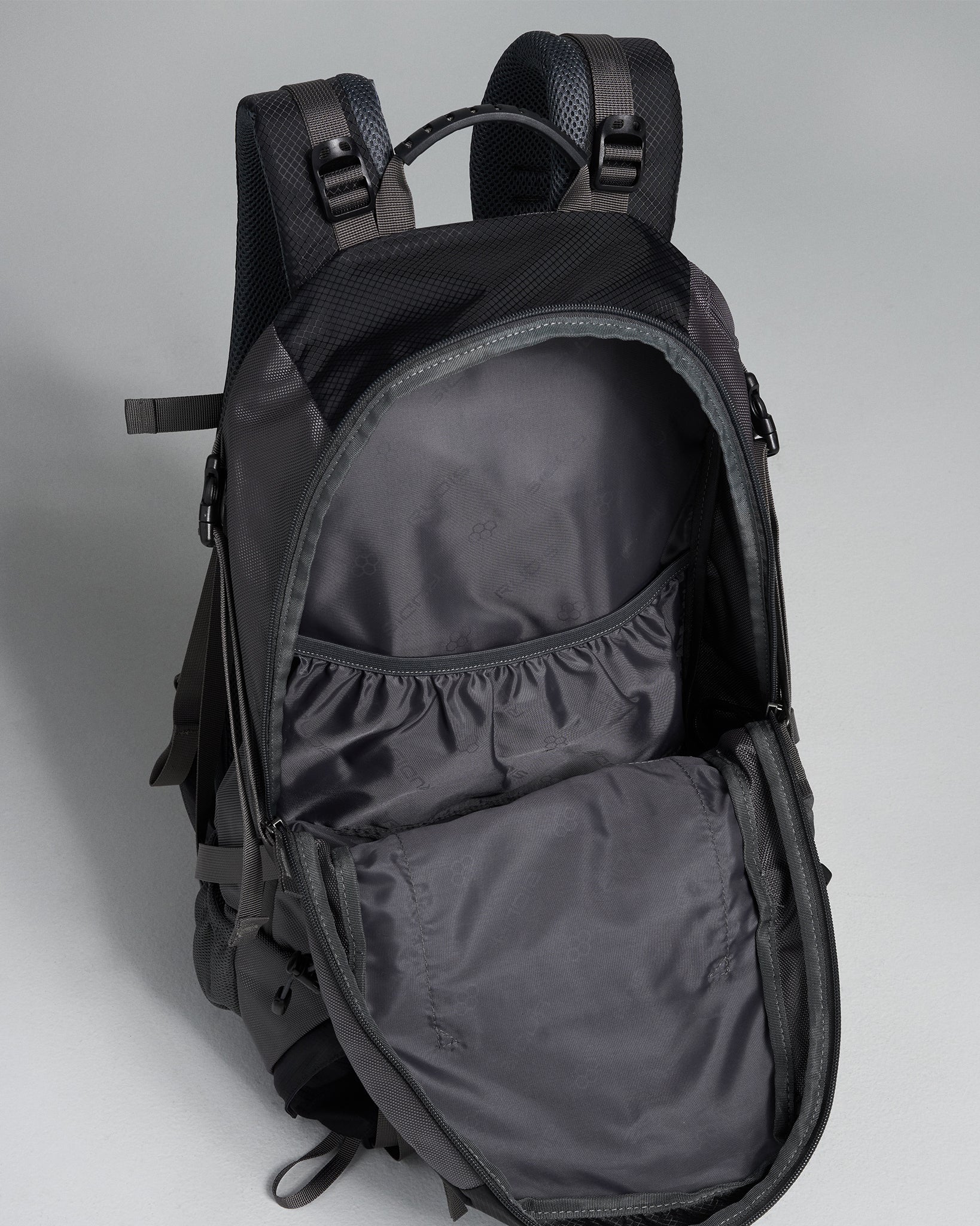 A black backpack with an open main compartment featuring a smooth inner lining and a mesh pocket