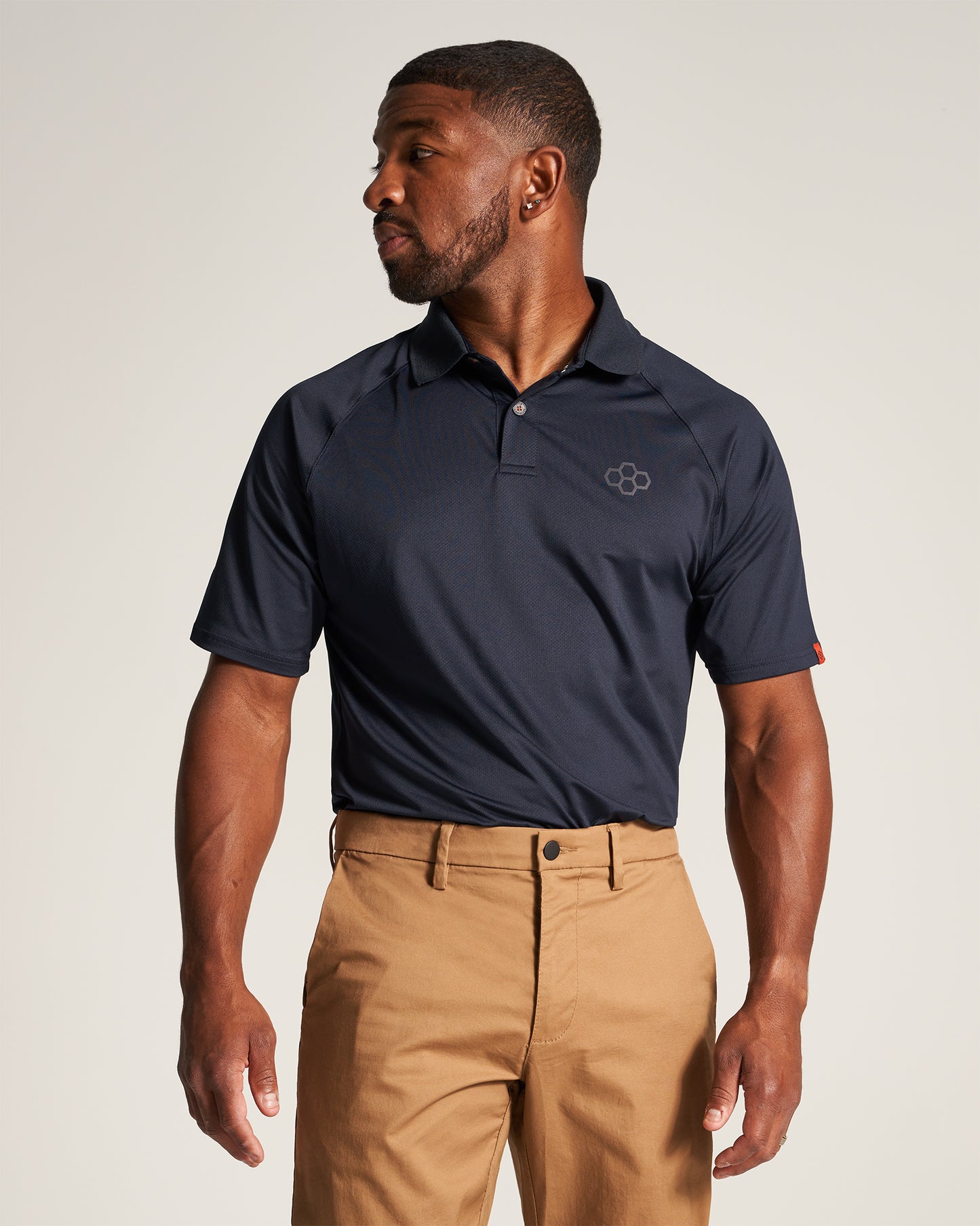 A man in a navy polo shirt and khaki pants poses confidently showcasing a modern casual outfit suitable for various occasions