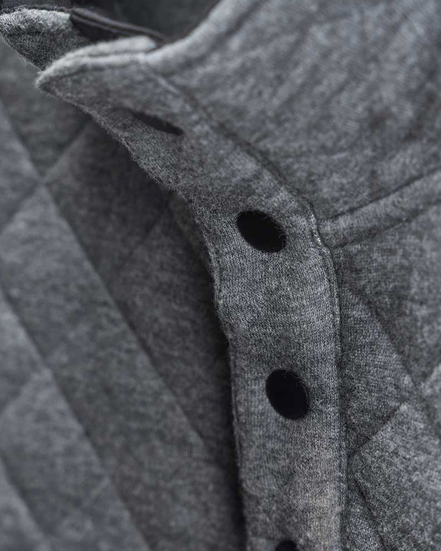 Close-up view of a gray quilted garment featuring prominent black buttons and textured fabric detail