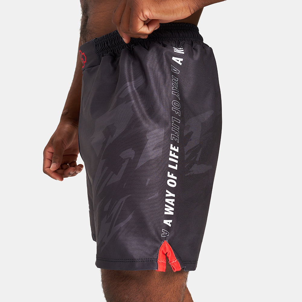 A close-up view of a man wearing black athletic shorts featuring a dynamic design and a bold message along the side showcasing the vibrant red accents