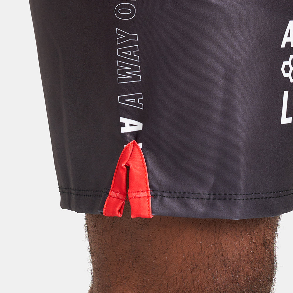 A close-up view of black athletic shorts featuring red accents and a motivational text design