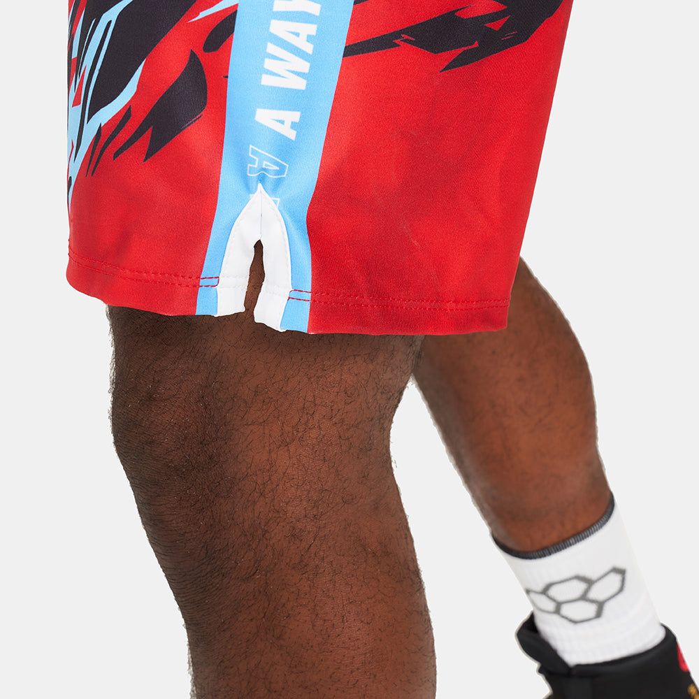 This image displays a close-up of vibrant red athletic shorts featuring dynamic black designs and blue accents worn by an athlete showcasing their style and functionality during a workout or sporting event