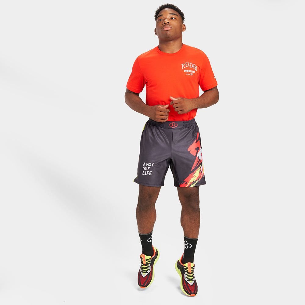 A young athlete is dressed in a vibrant red t-shirt paired with black shorts featuring bold designs preparing for a workout or competition