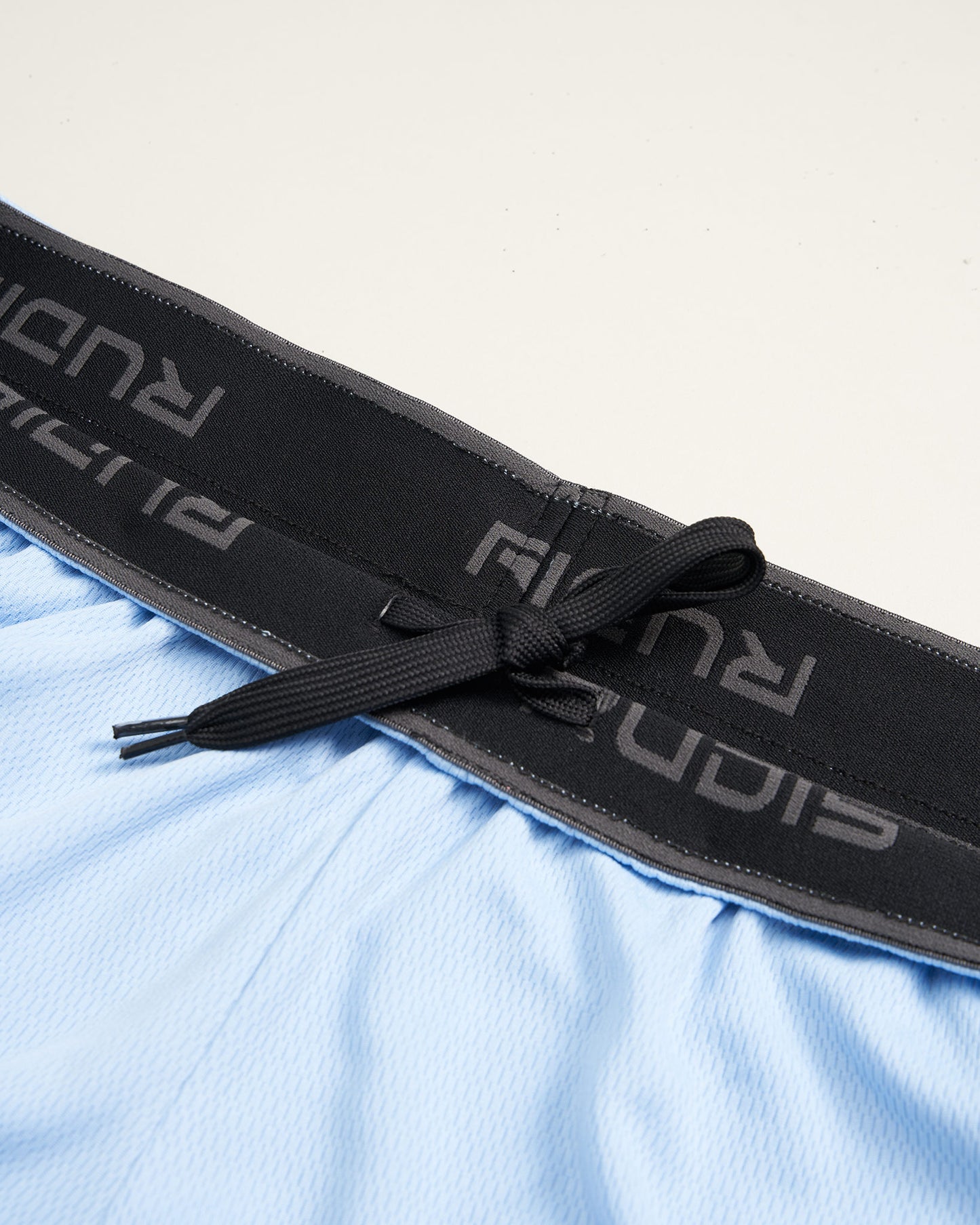 A close-up view of light blue athletic shorts featuring a black elastic waistband with drawstrings for adjustable fit