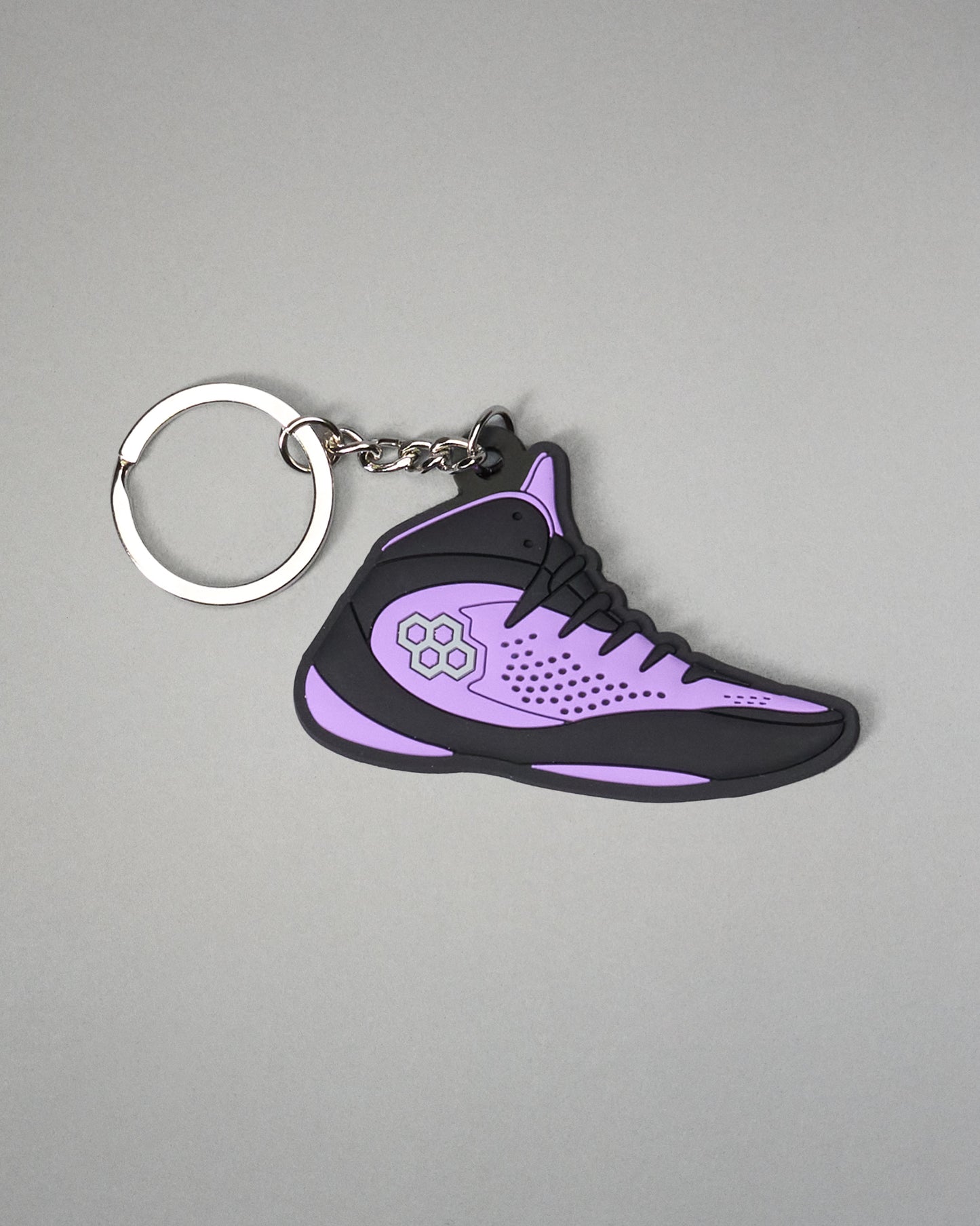 Purple and black shoe-shaped keychain on a gray background