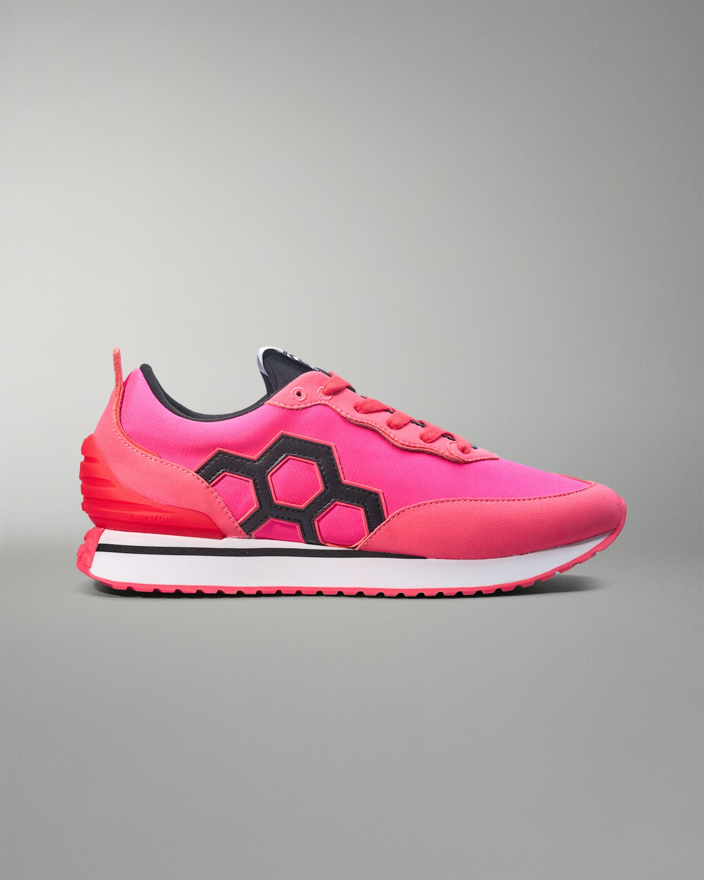 Pink sneaker with black hexagonal design on a gray background