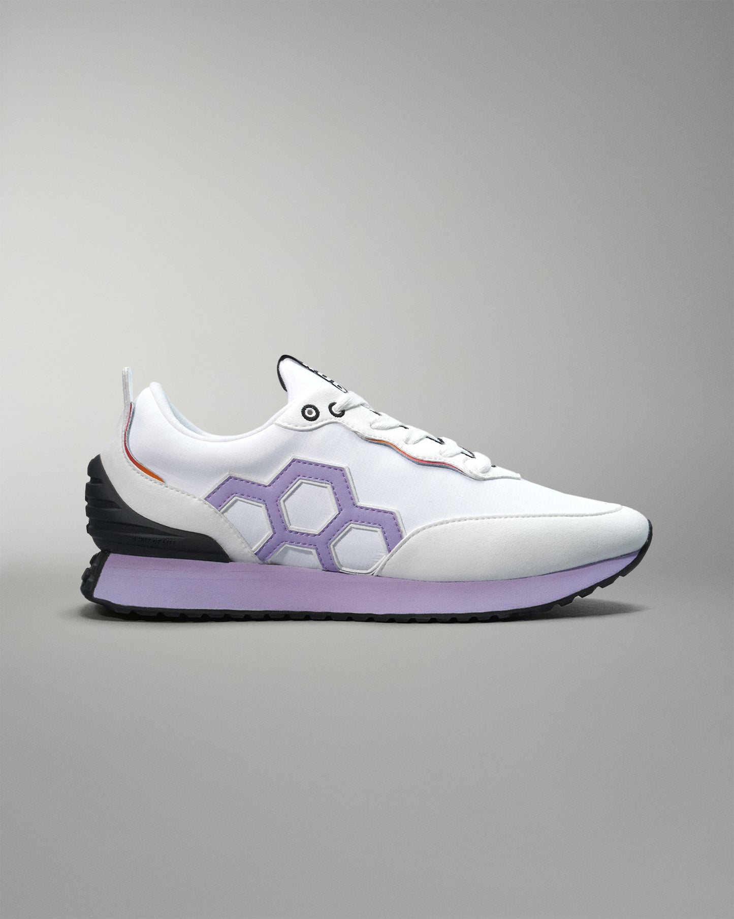 White sneaker with purple sole on a gray background