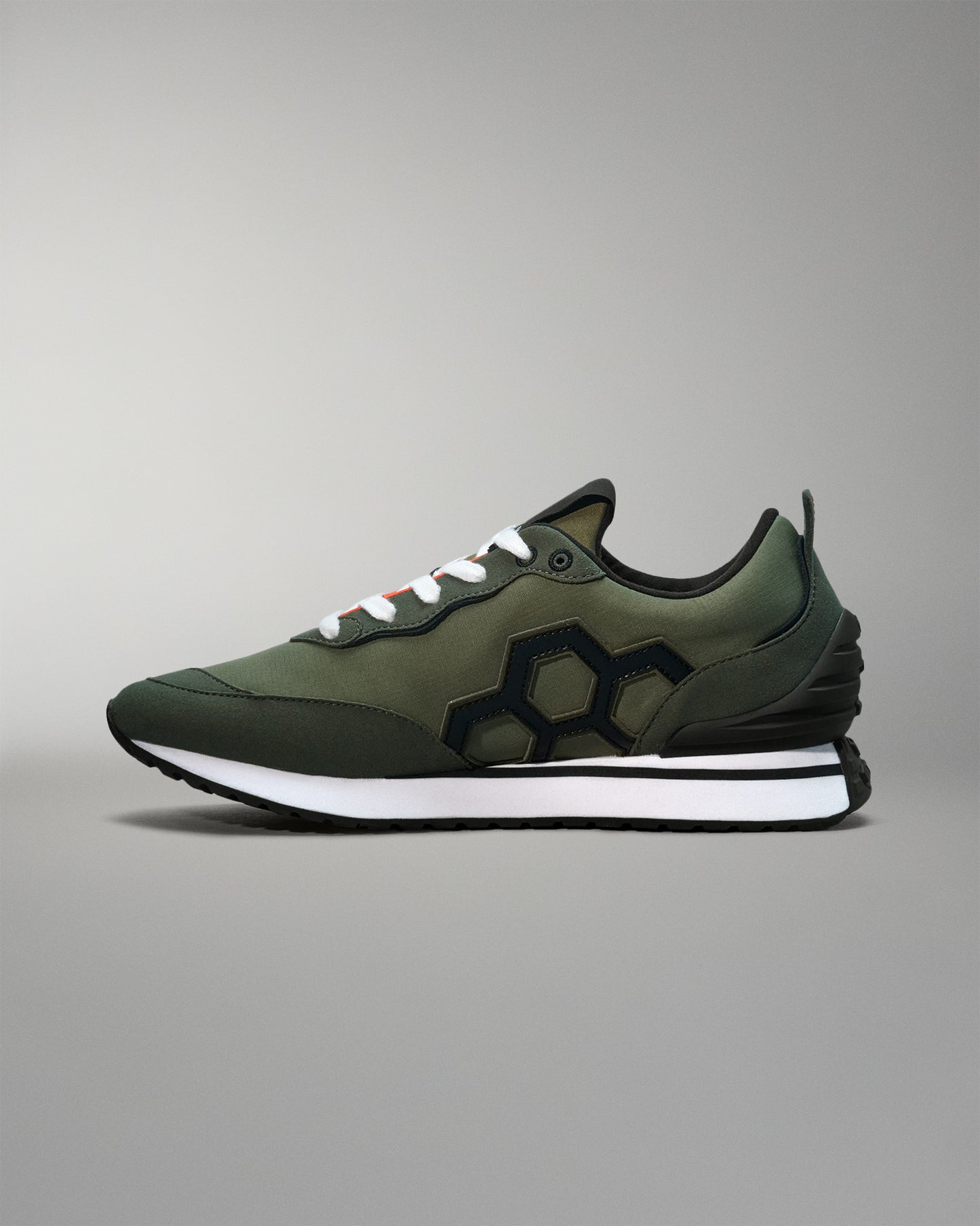 Green sneaker with black sole on a gray background