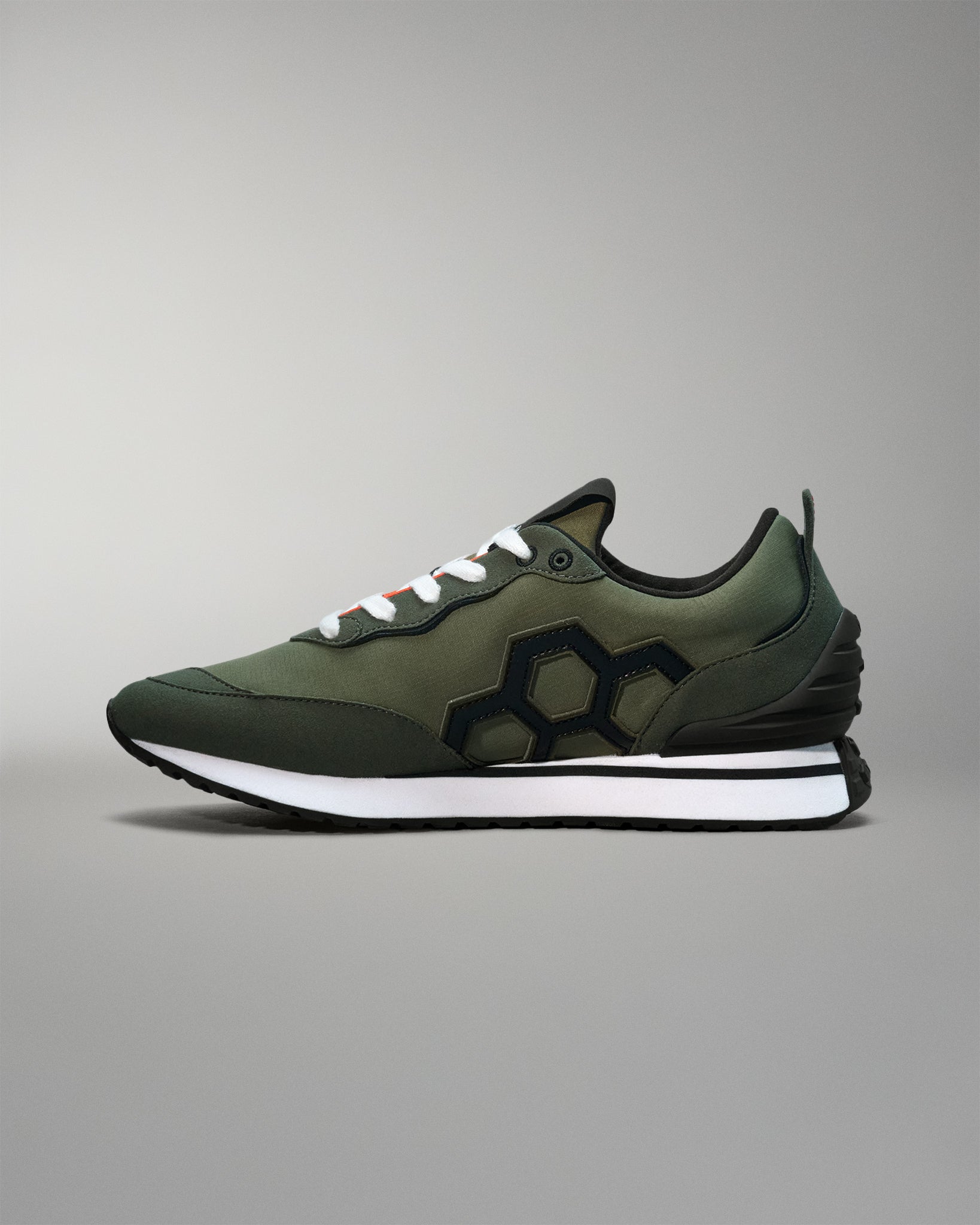 Green sneaker with black sole on a gray background