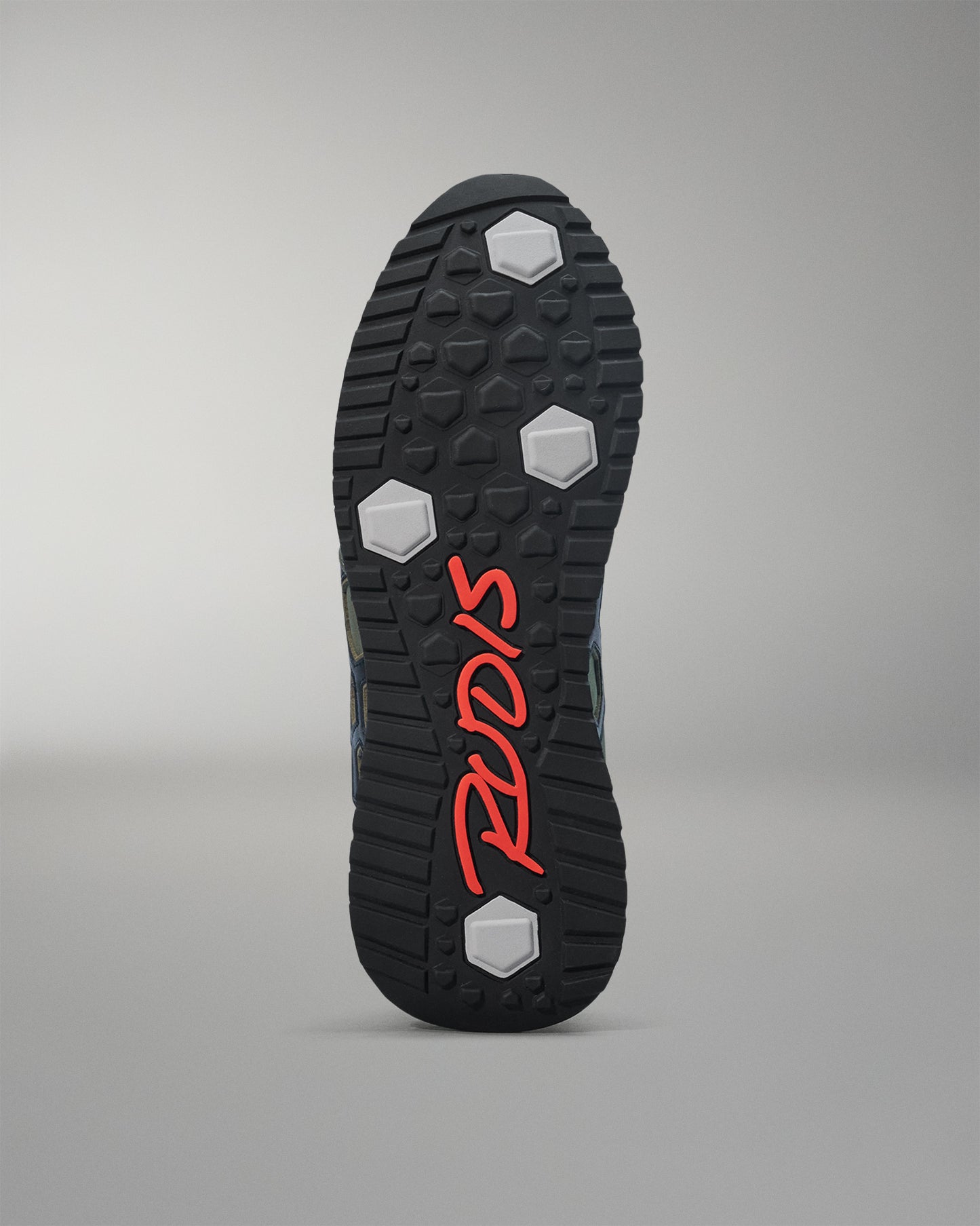 Close-up of a shoe sole with red branding on a gray background