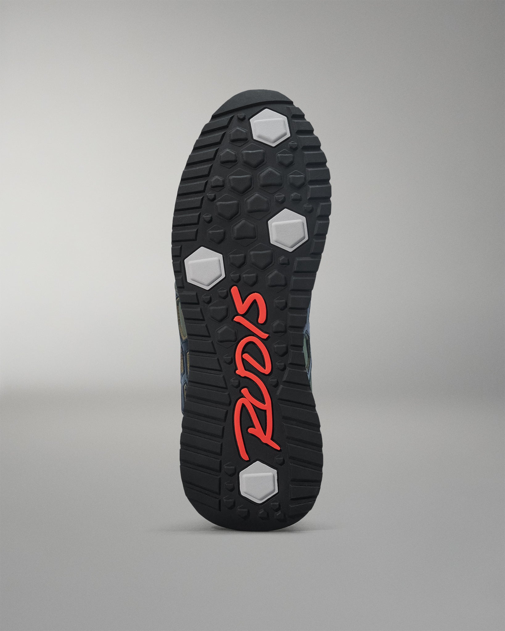 Close-up of a shoe sole with red branding on a gray background