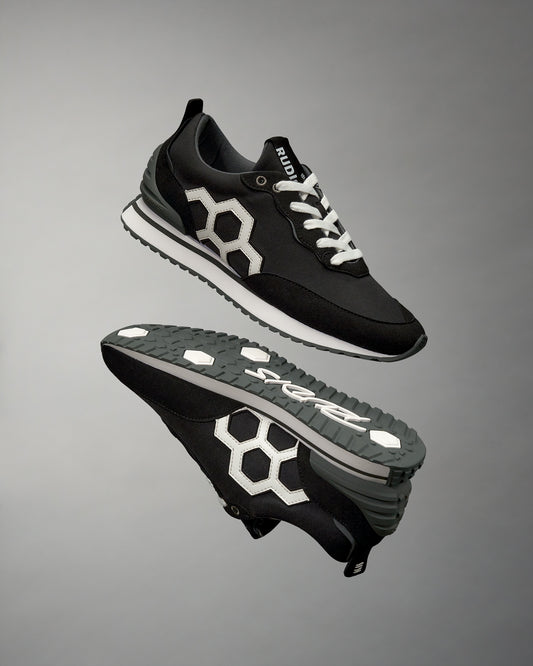 A pair of black RUDIS street lifestyle shoes with a prominent white hexagonal logo on the side, displayed against a grey background.