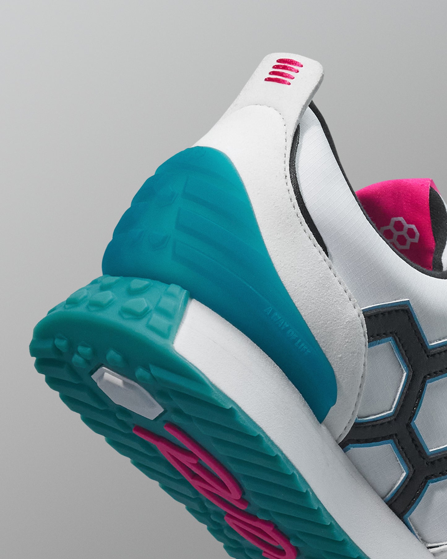 Close-up of a sneaker with teal sole and pink accents on a gray background