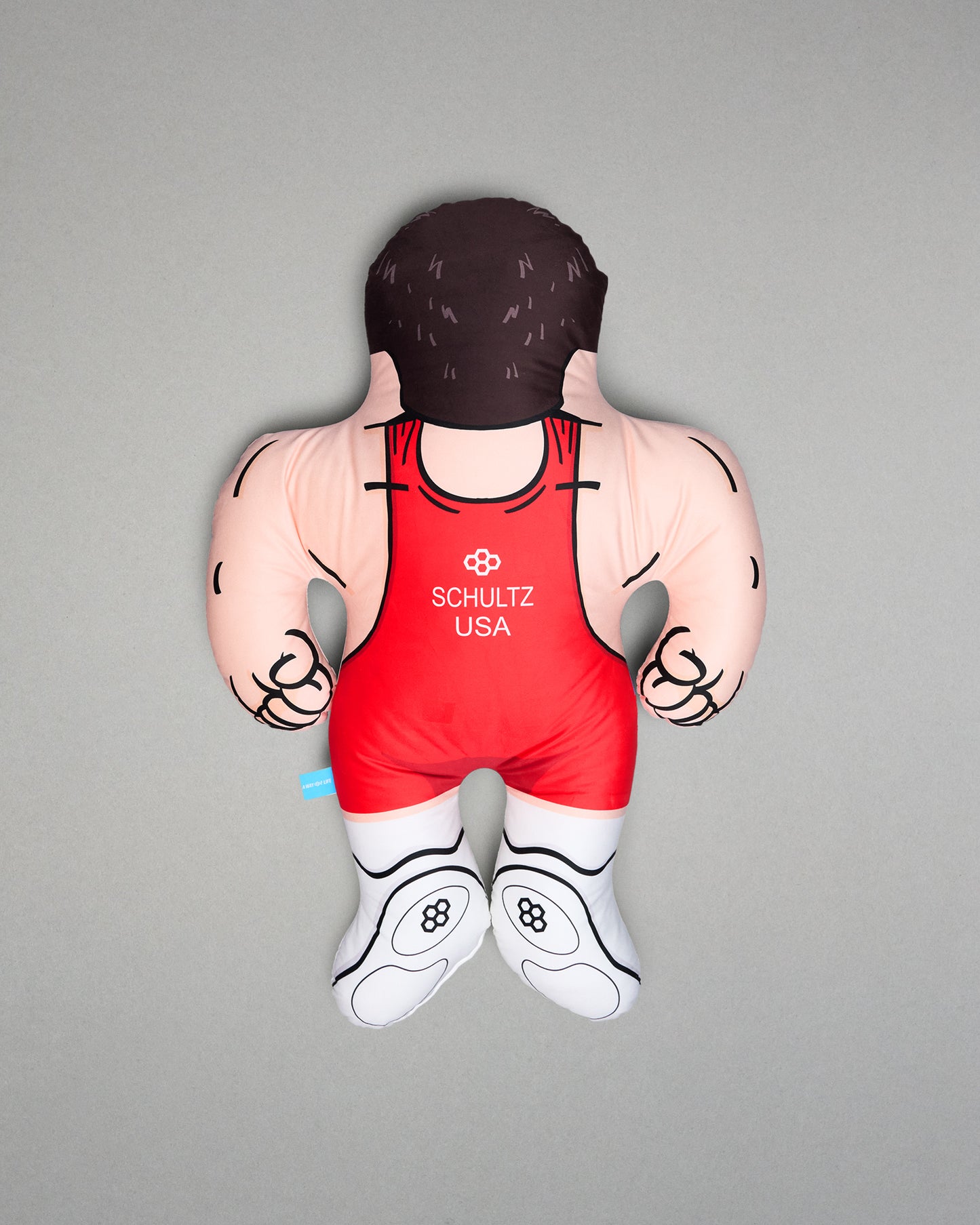 Pillow of a wrestler in a red singlet with 'Shultz USA' branding on a gray background