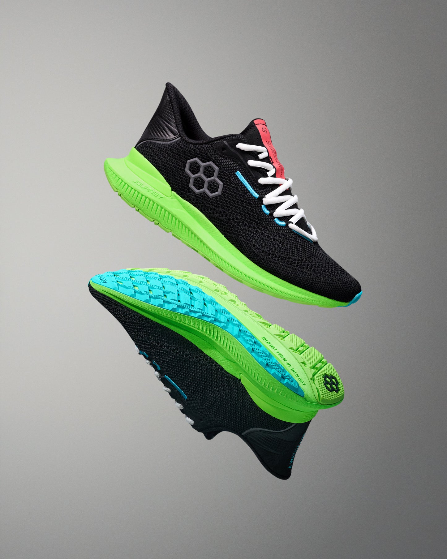 Black running shoes with green and blue soles on a gray background
