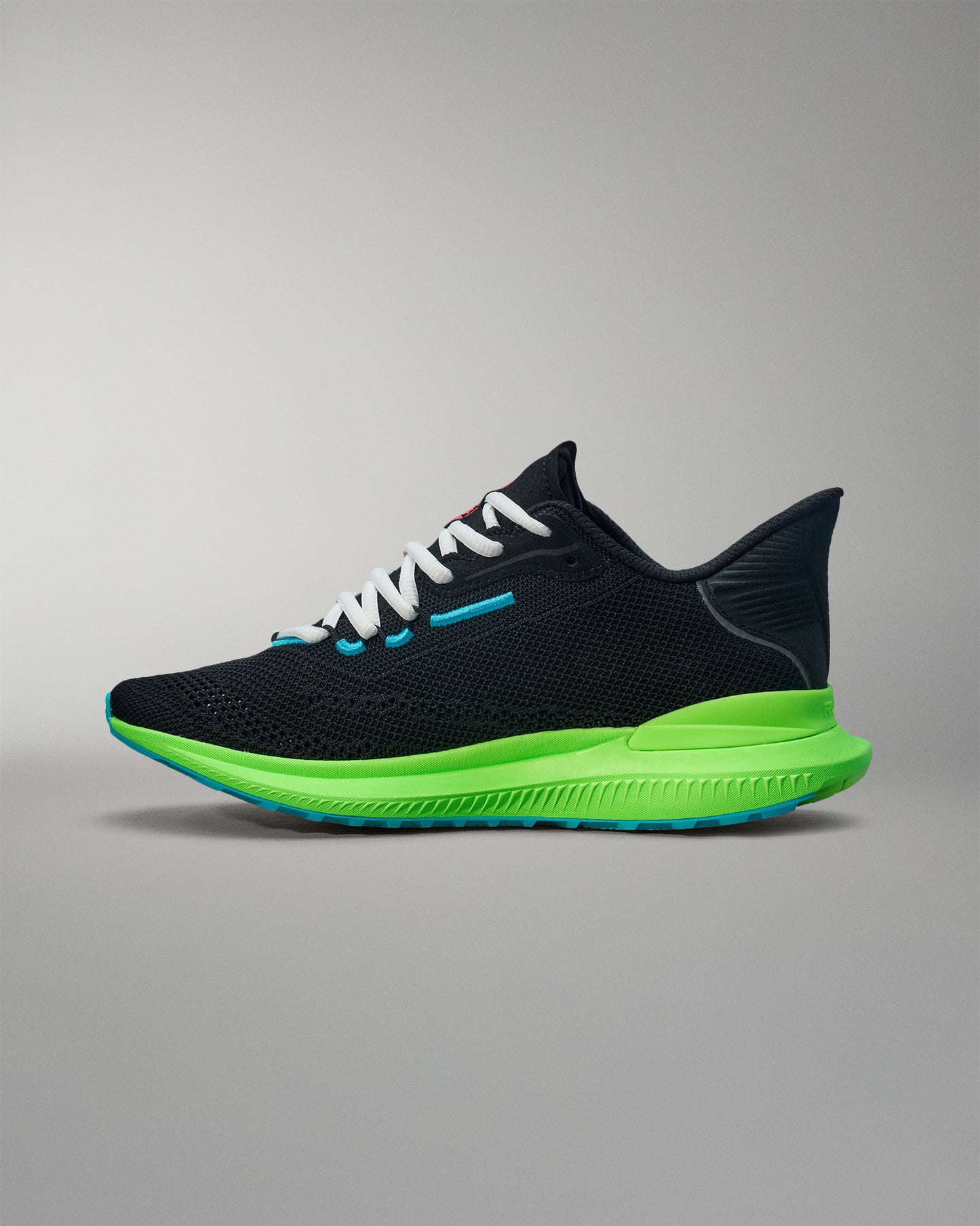 Black running shoe with green sole on a gray background