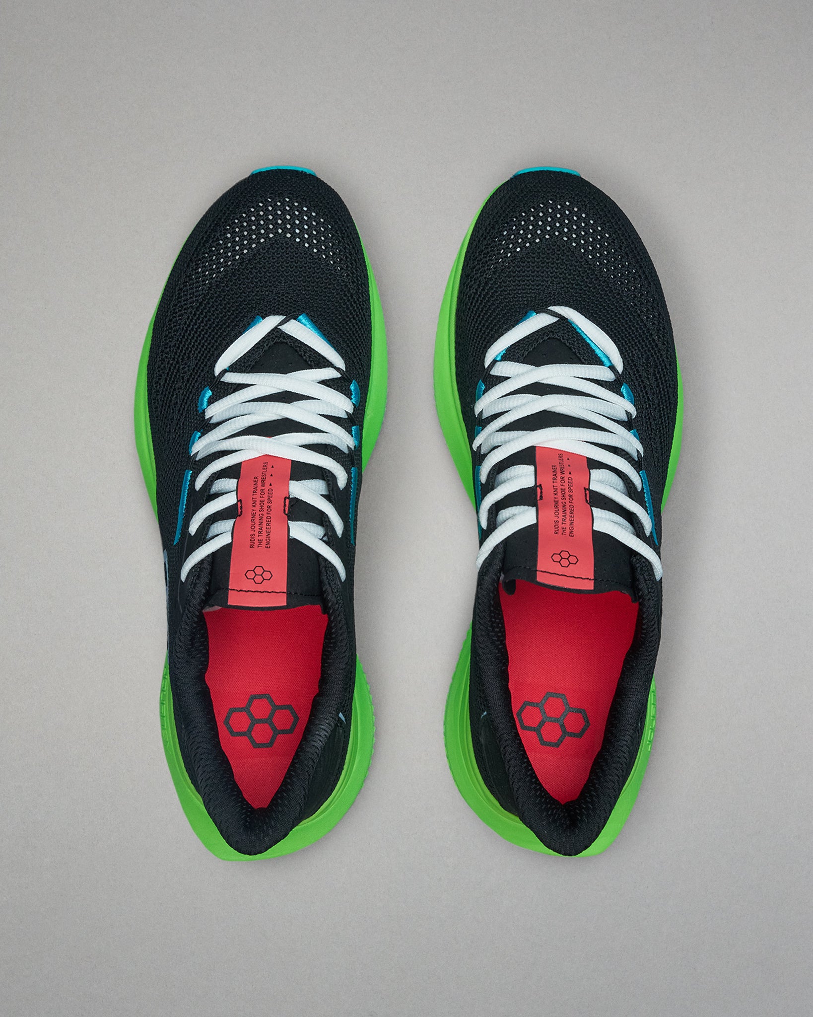 Black running shoes with green soles and red tongue on a gray background