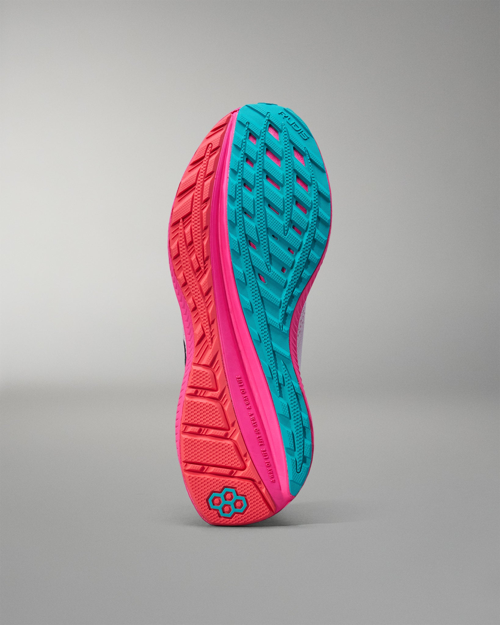 Close-up of a pink and teal athletic shoe sole on a gray background