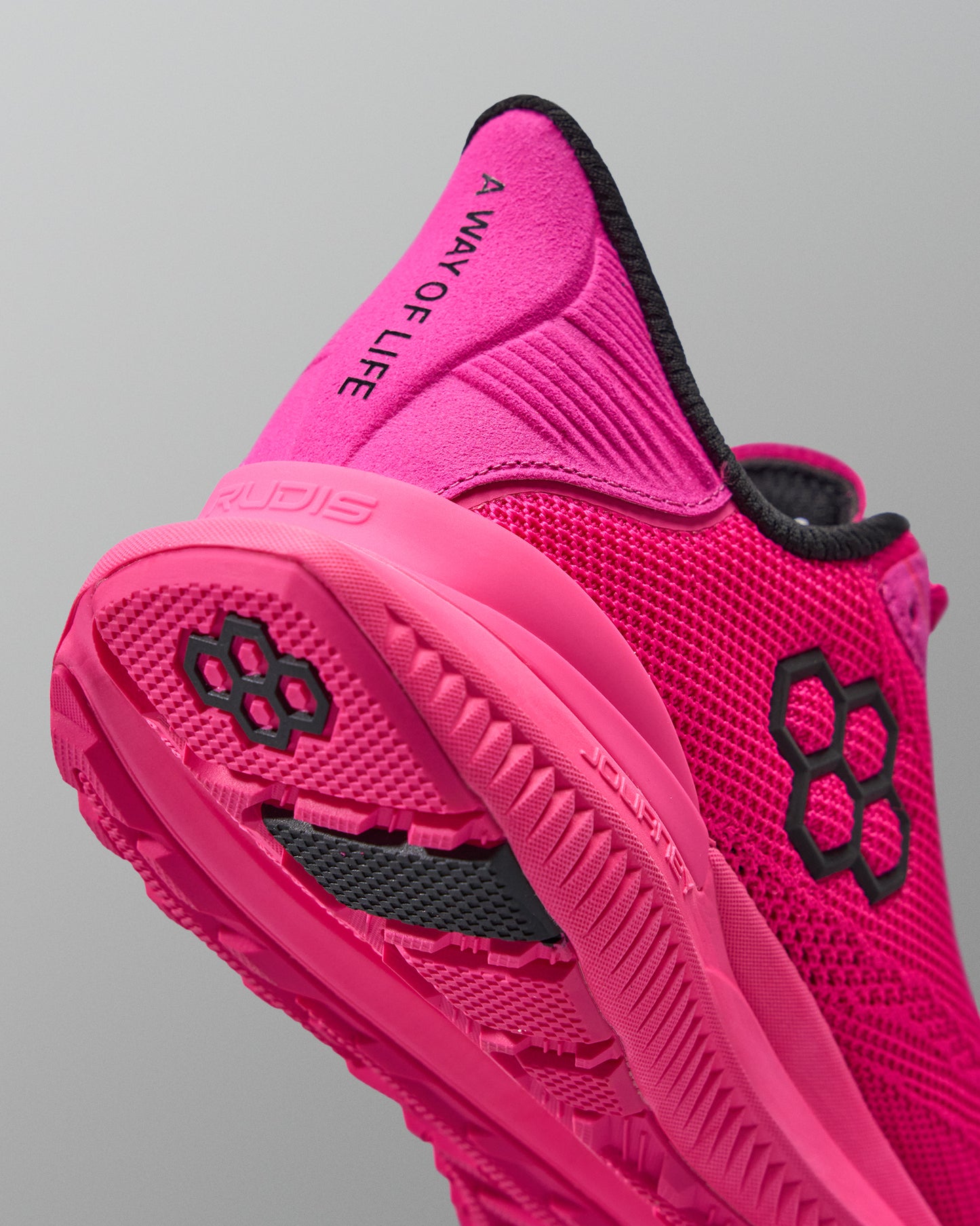 Pink athletic shoe with black text and logo on a gray background with black RUDIS logo