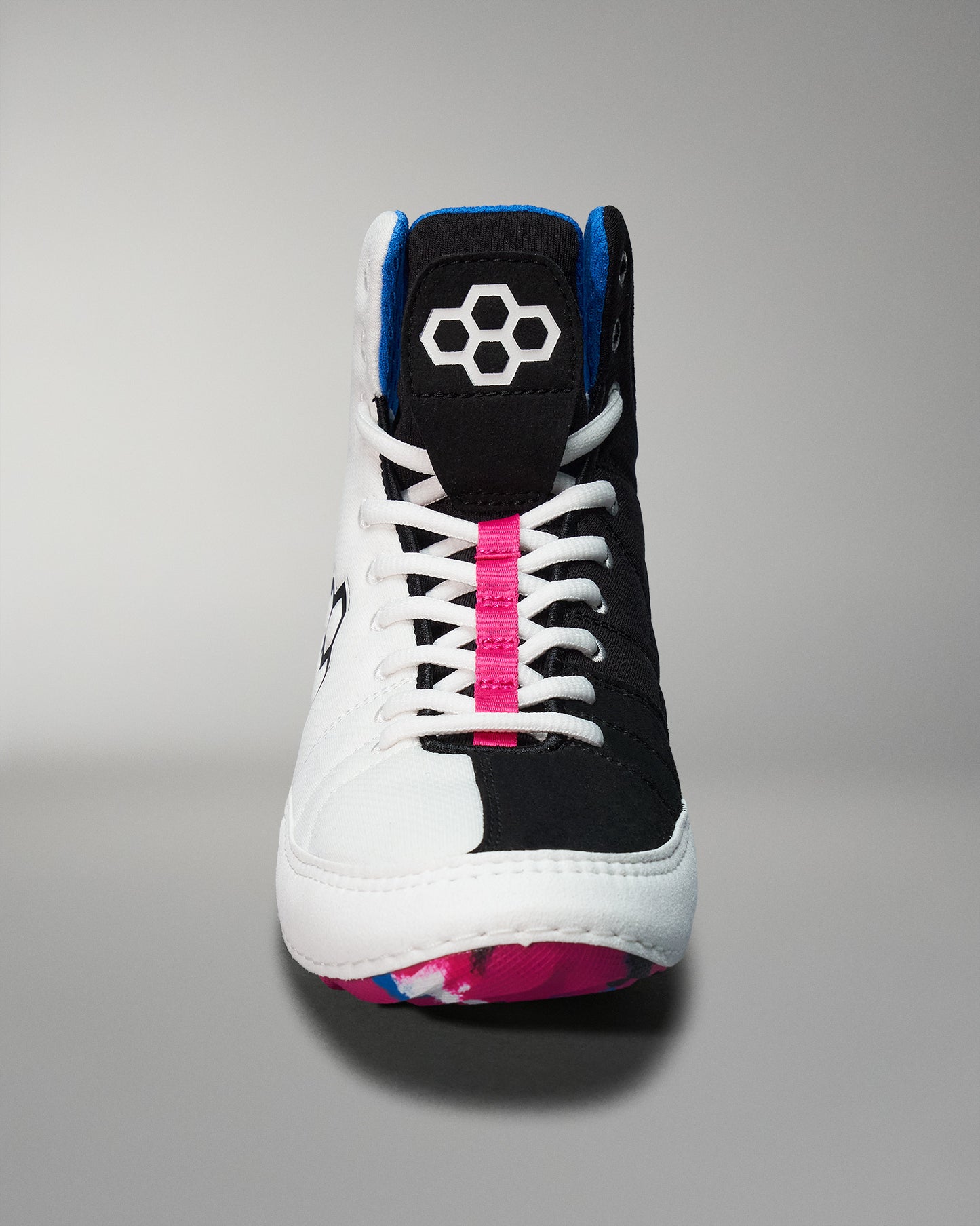 A front view of a high-top athletic shoe with a black and white design, highlighted by a pink stripe and a blue accent, featuring a patterned sole.