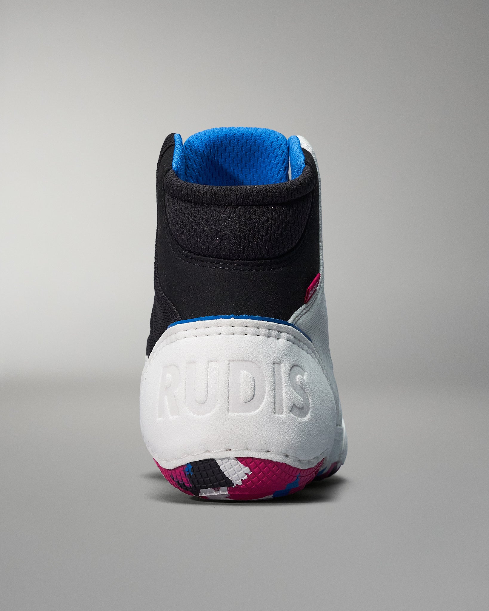 A back view of a high-top wrestling shoe with a black and white design, highlighted by a pink stripe and a blue accent, featuring a patterned sole.