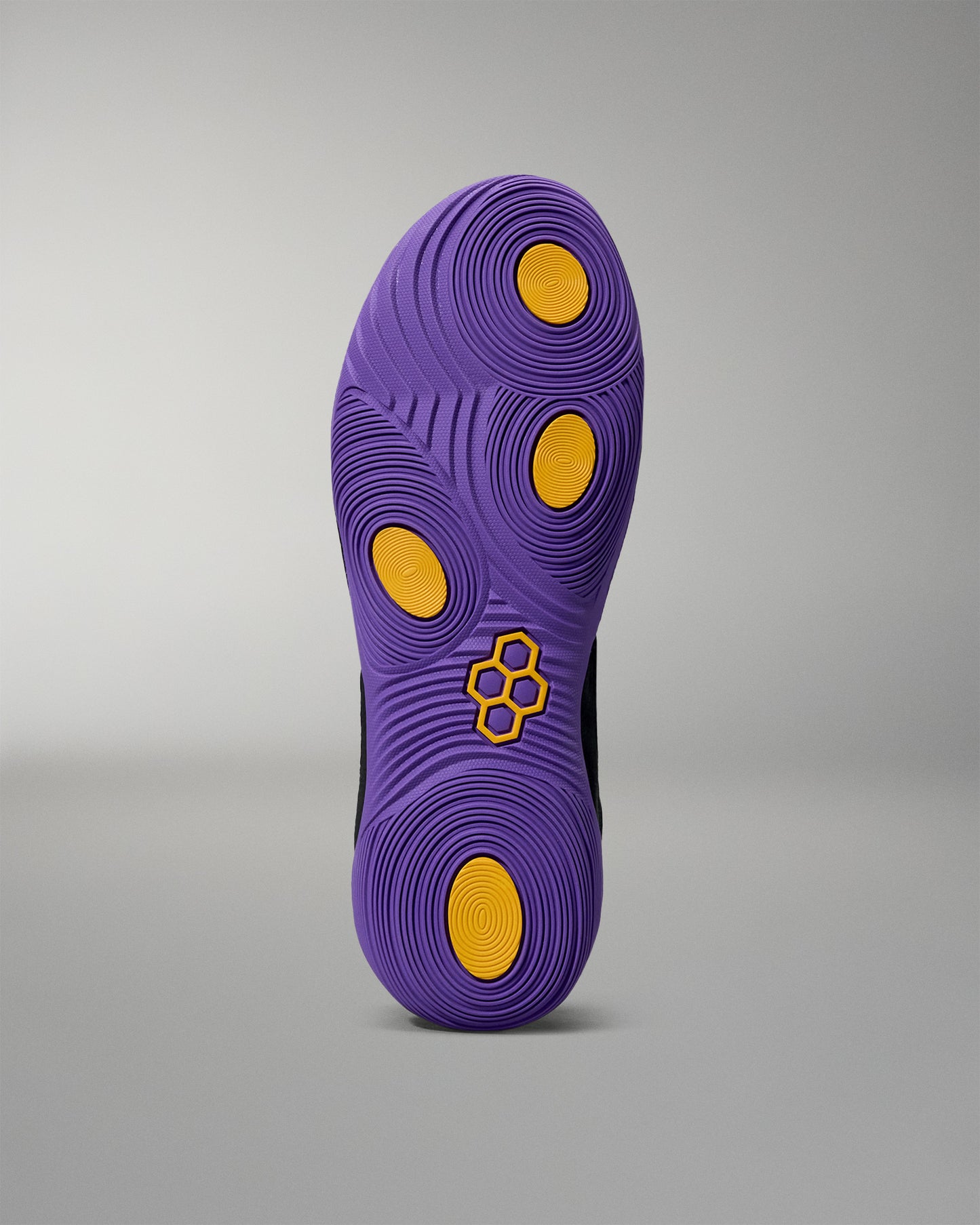Purple shoe sole with yellow dots and a logo on a gray background