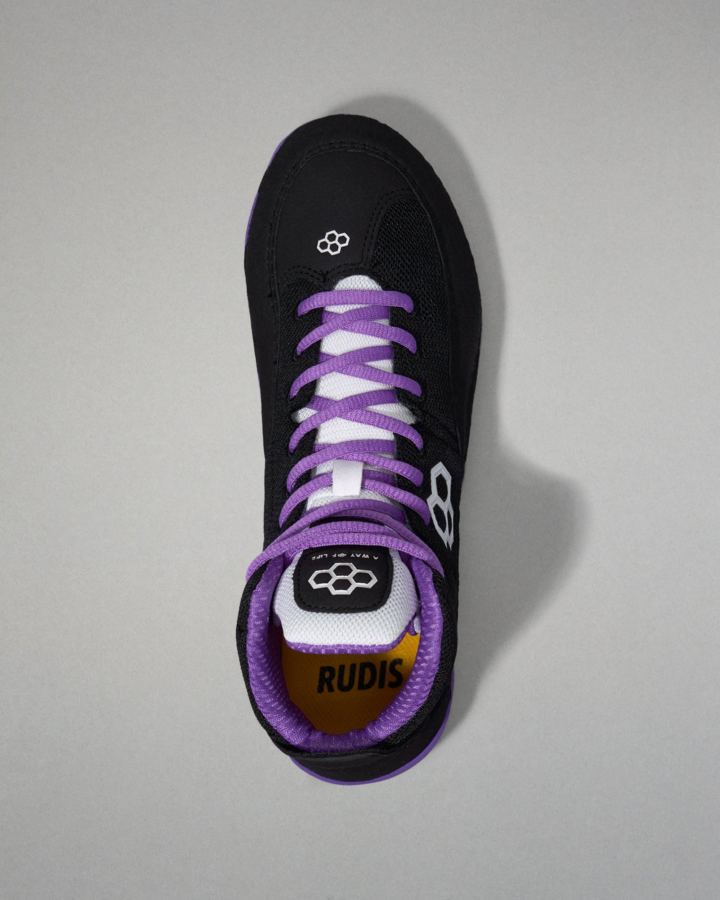 Black shoe with purple laces on a gray background