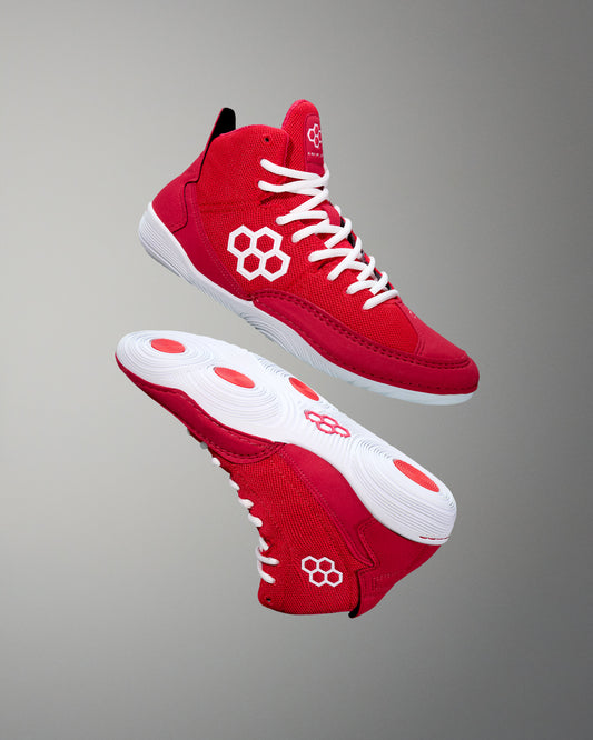 A pair of crimson red adult wrestling shoes with white laces and a distinctive flower logo on the side.