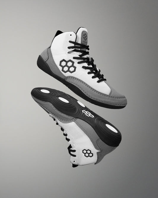 A pair of white and black RUDIS Courage adult wrestling shoes with a micro-suede rand and a stable outsole.