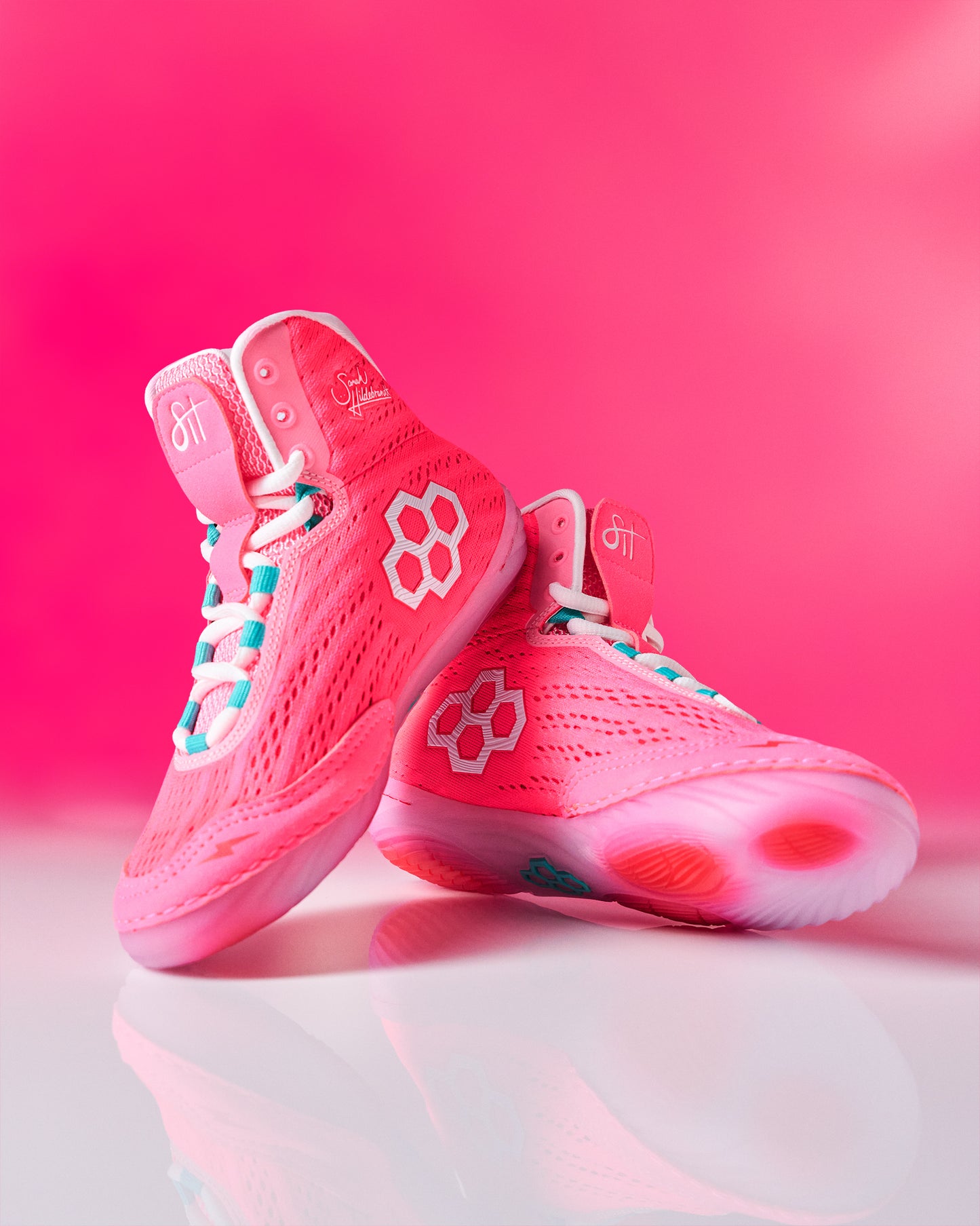 Pink wrestling shoes with RUDIS brand logo on a pink background