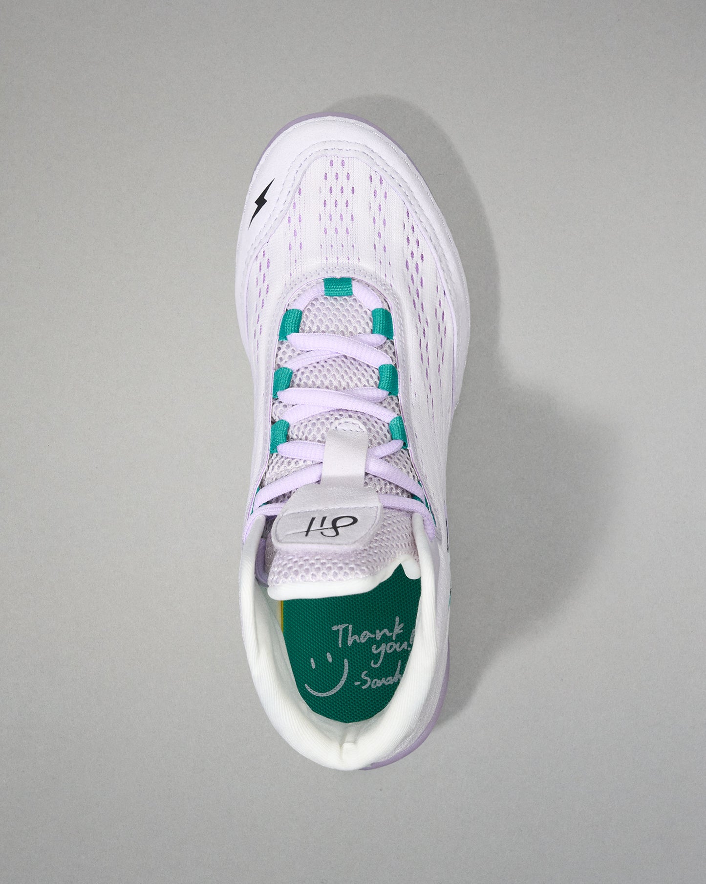 White sneaker with green accents on a gray background