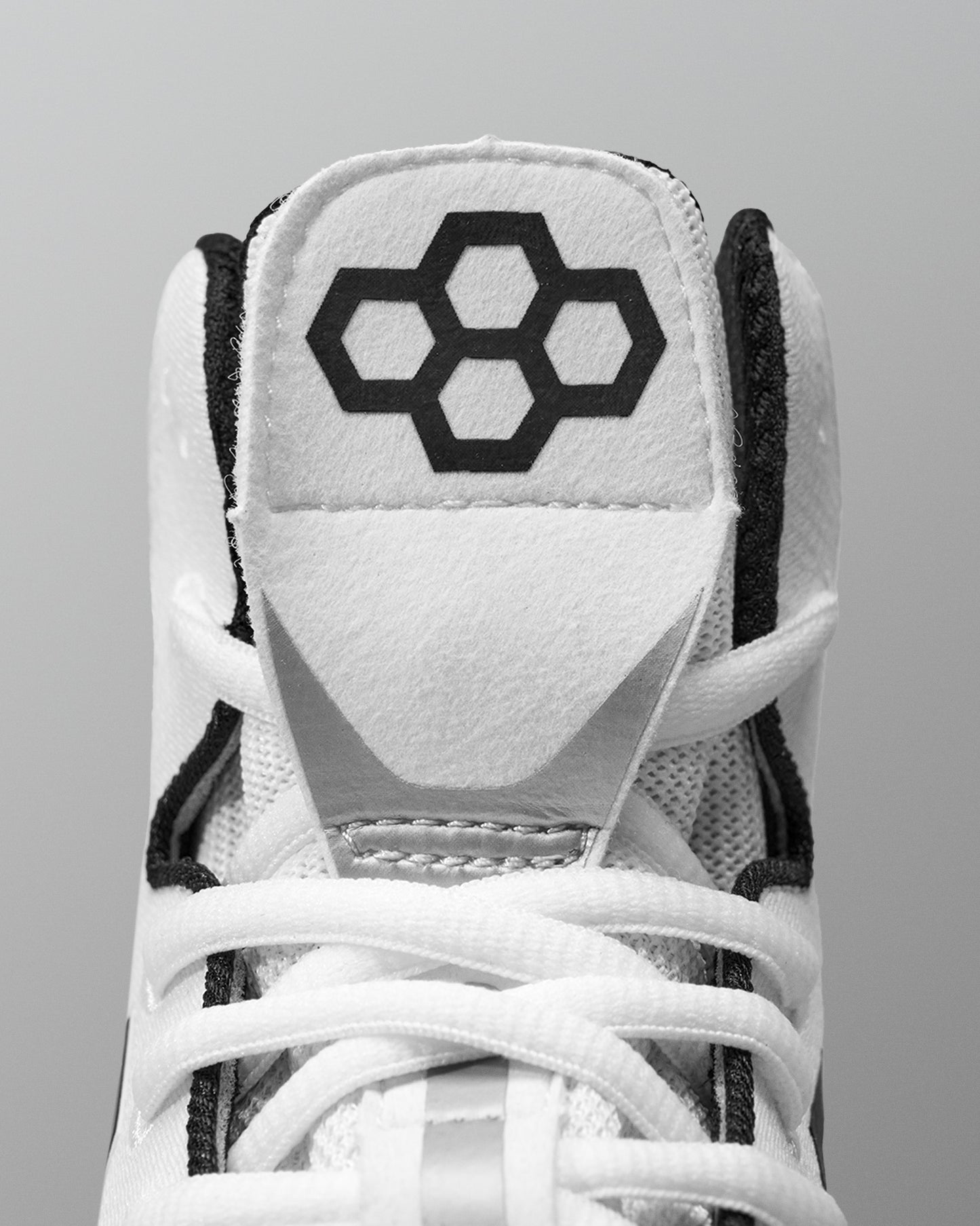 White Wrestling shoe with black hexagonal logo on a gray background