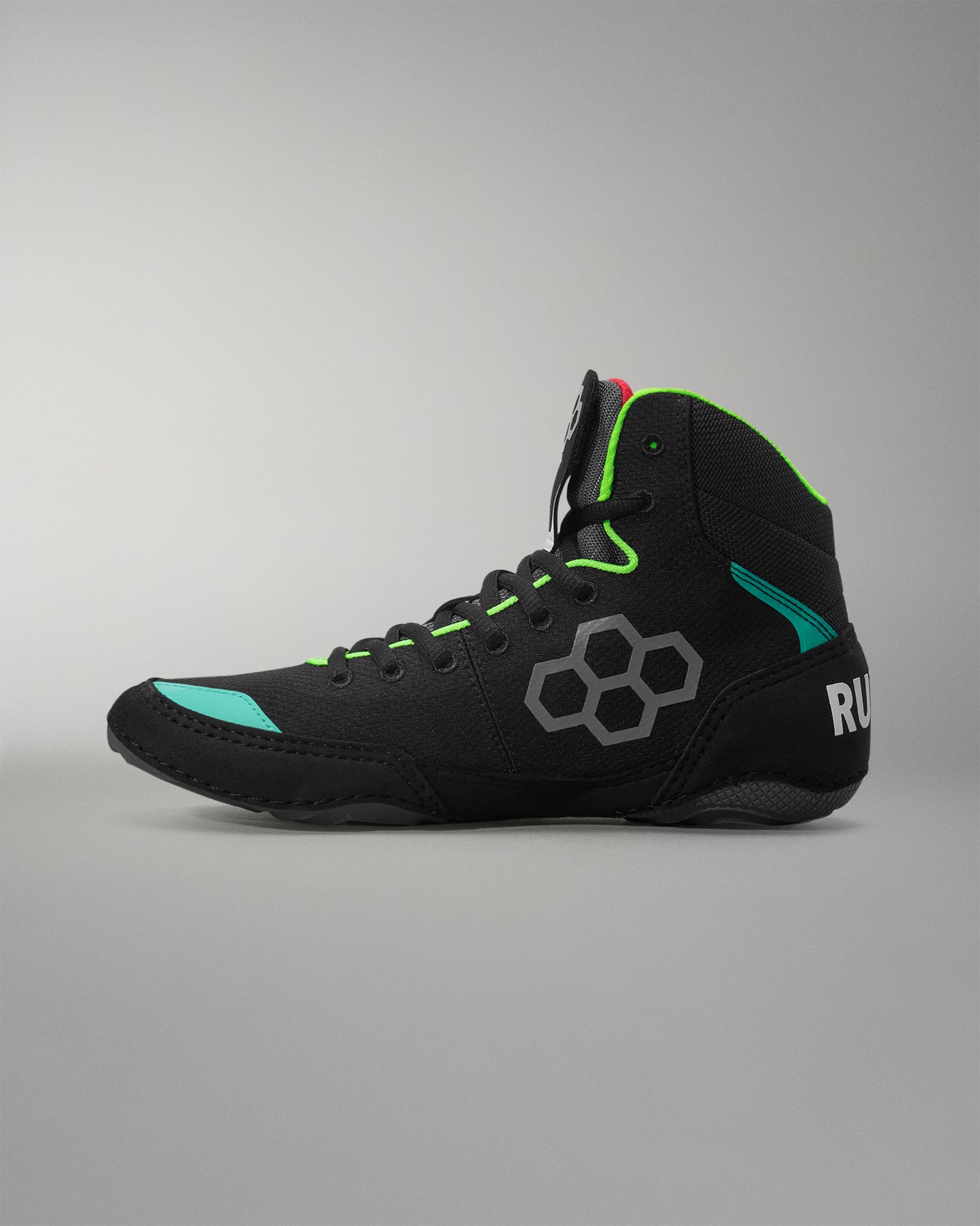 Black wrestling shoe with green accents on a gray background
