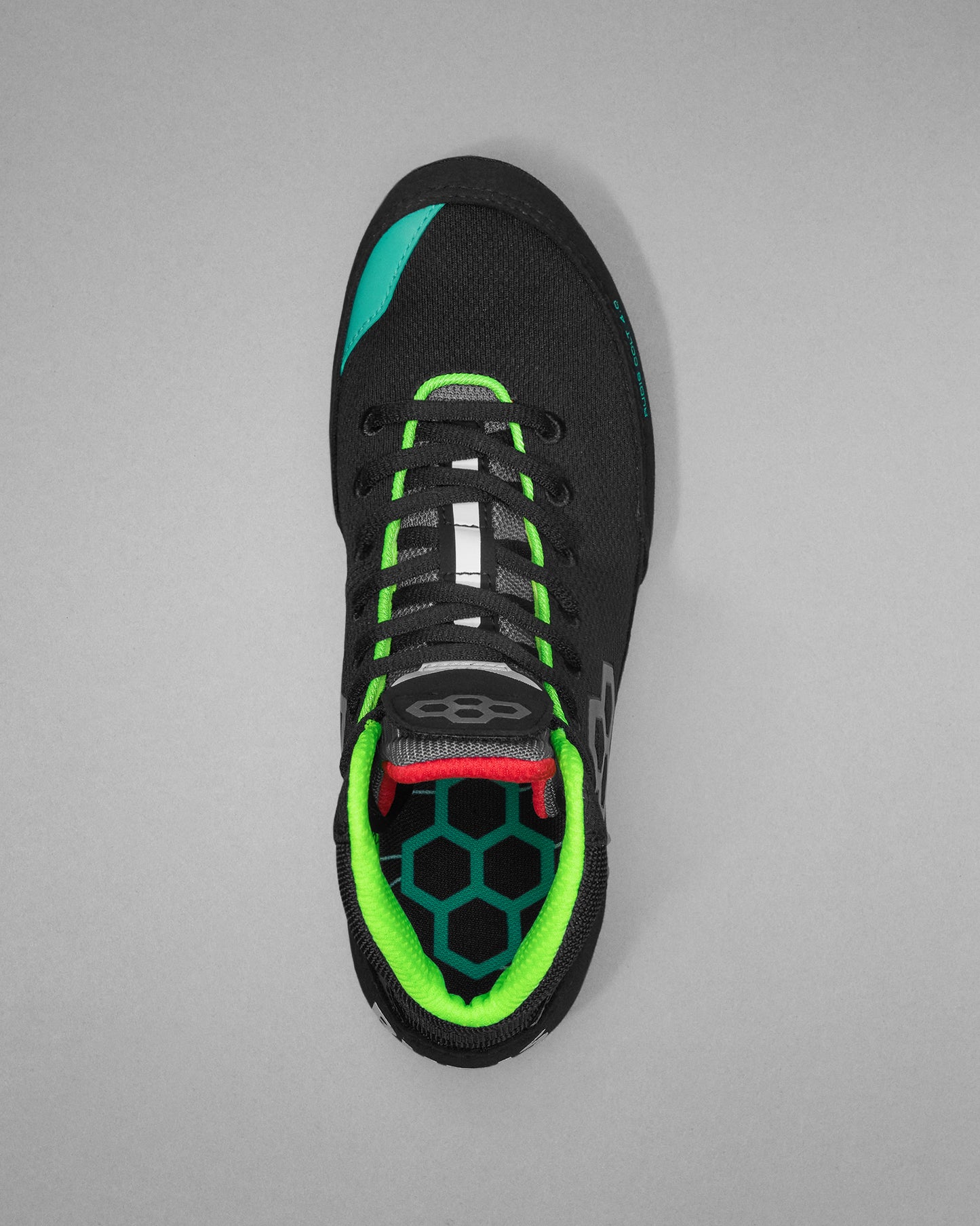 Black wrestling shoe with green and red accents on a gray background