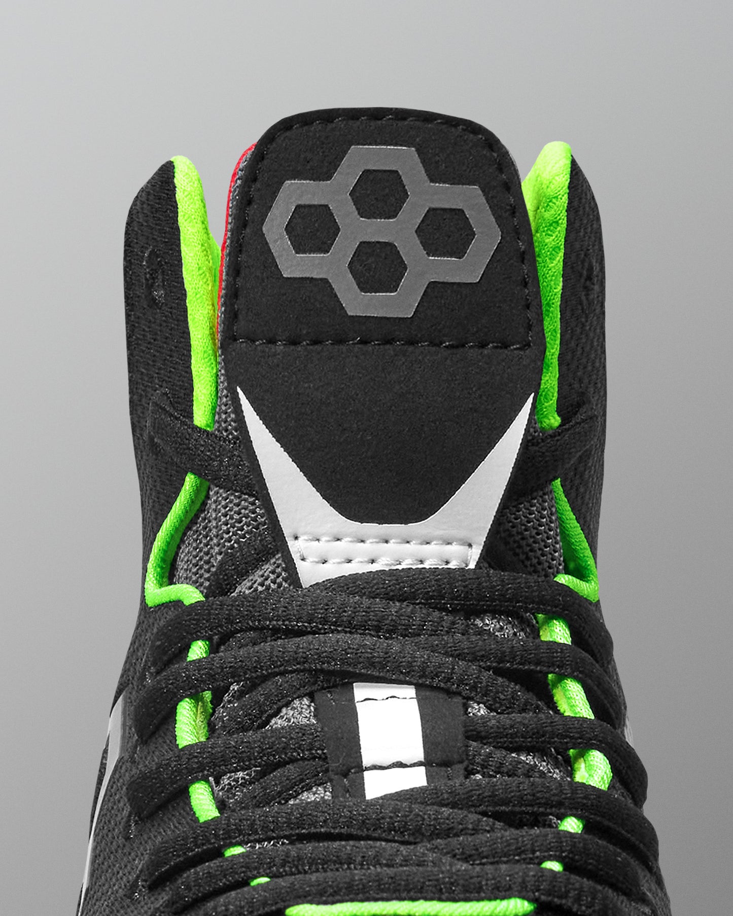 Black wrestling shoe with green accents and a brand logo on a gray background