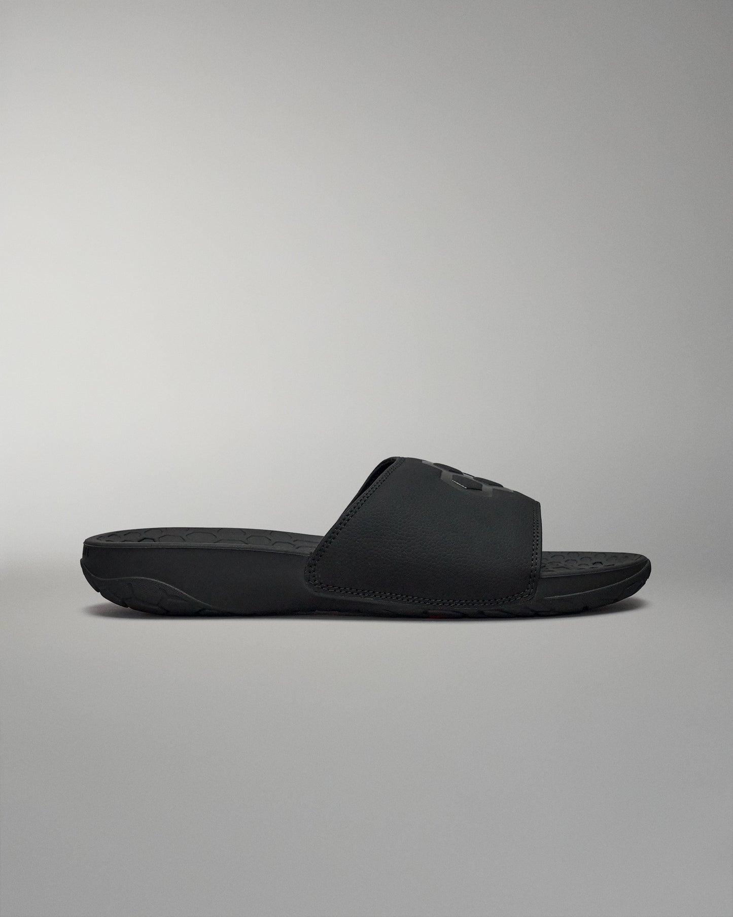 Side view of black slides sandal shoes on grey background.