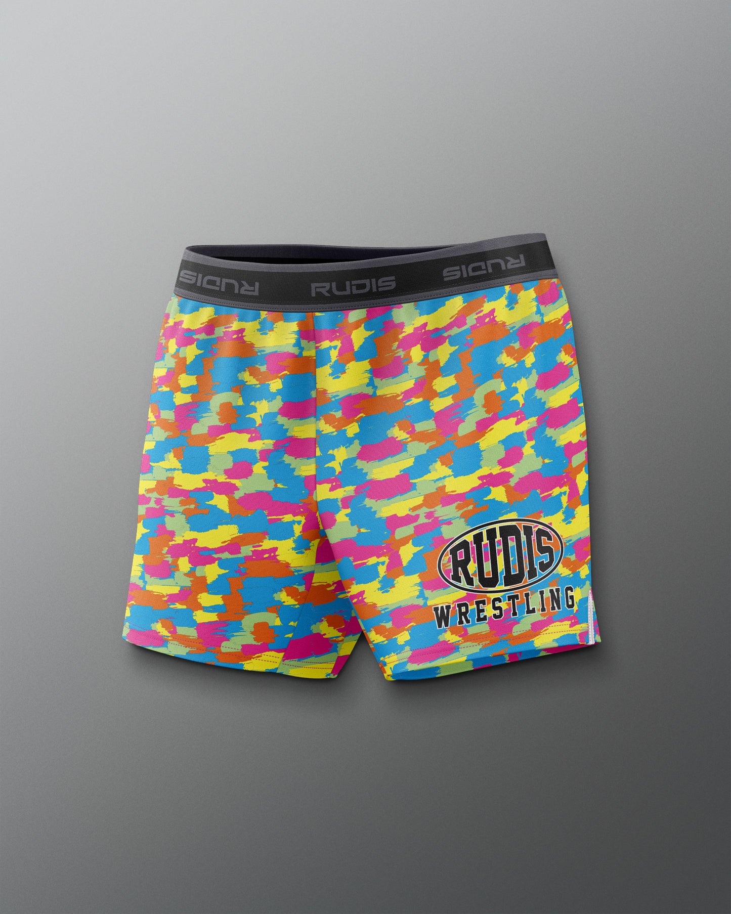 Colorful camouflage wrestling shorts with 'Rudis' branding on a gray background