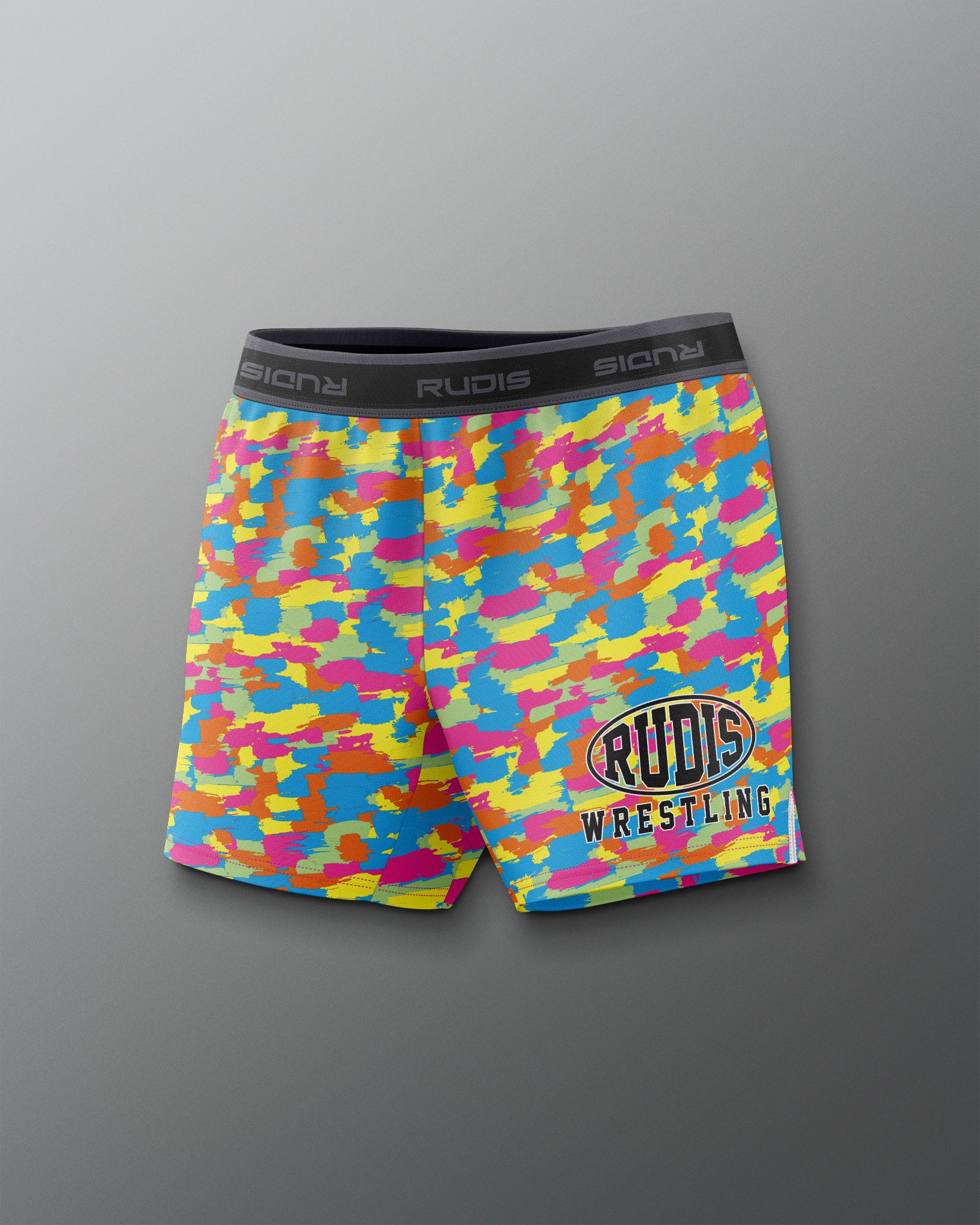 Colorful camouflage wrestling shorts with 'Rudis' branding on a gray background