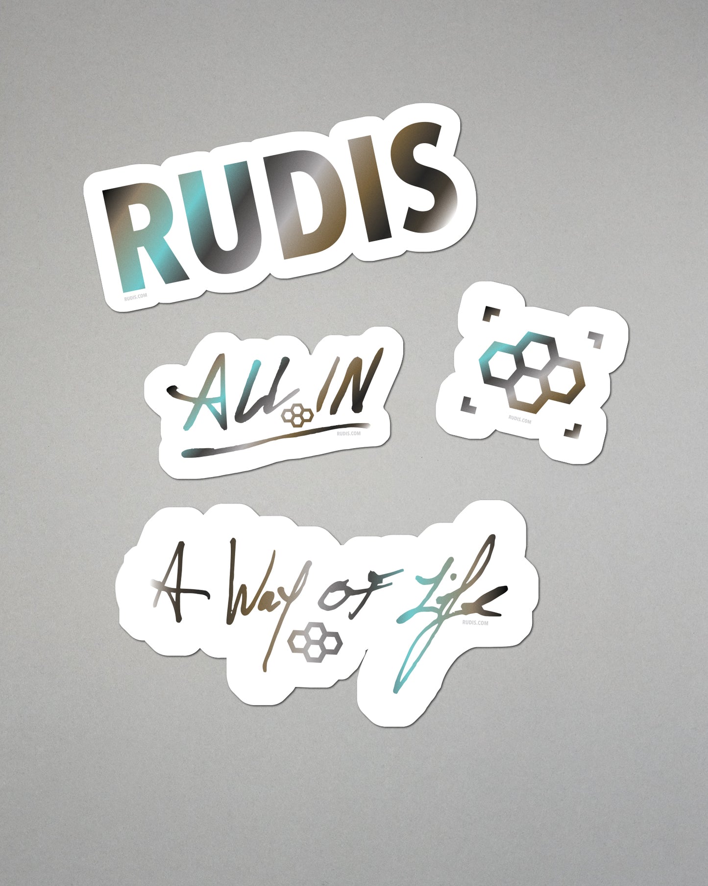 Four stickers with 'RUDIS', 'All In', and 'A Way of Life' text on a gray background