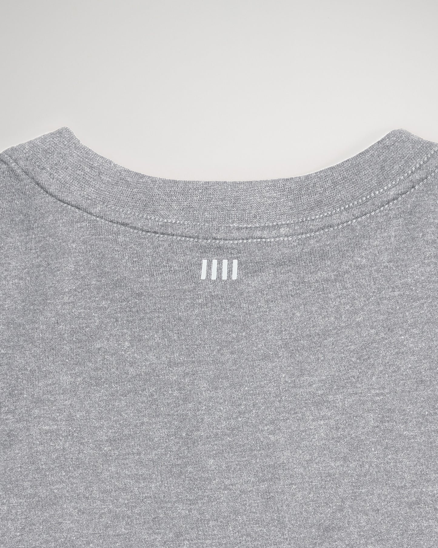 The back view of a gray T-shirt featuring a rounded neckline and three vertical white lines positioned near the collar indicating a simple yet modern design