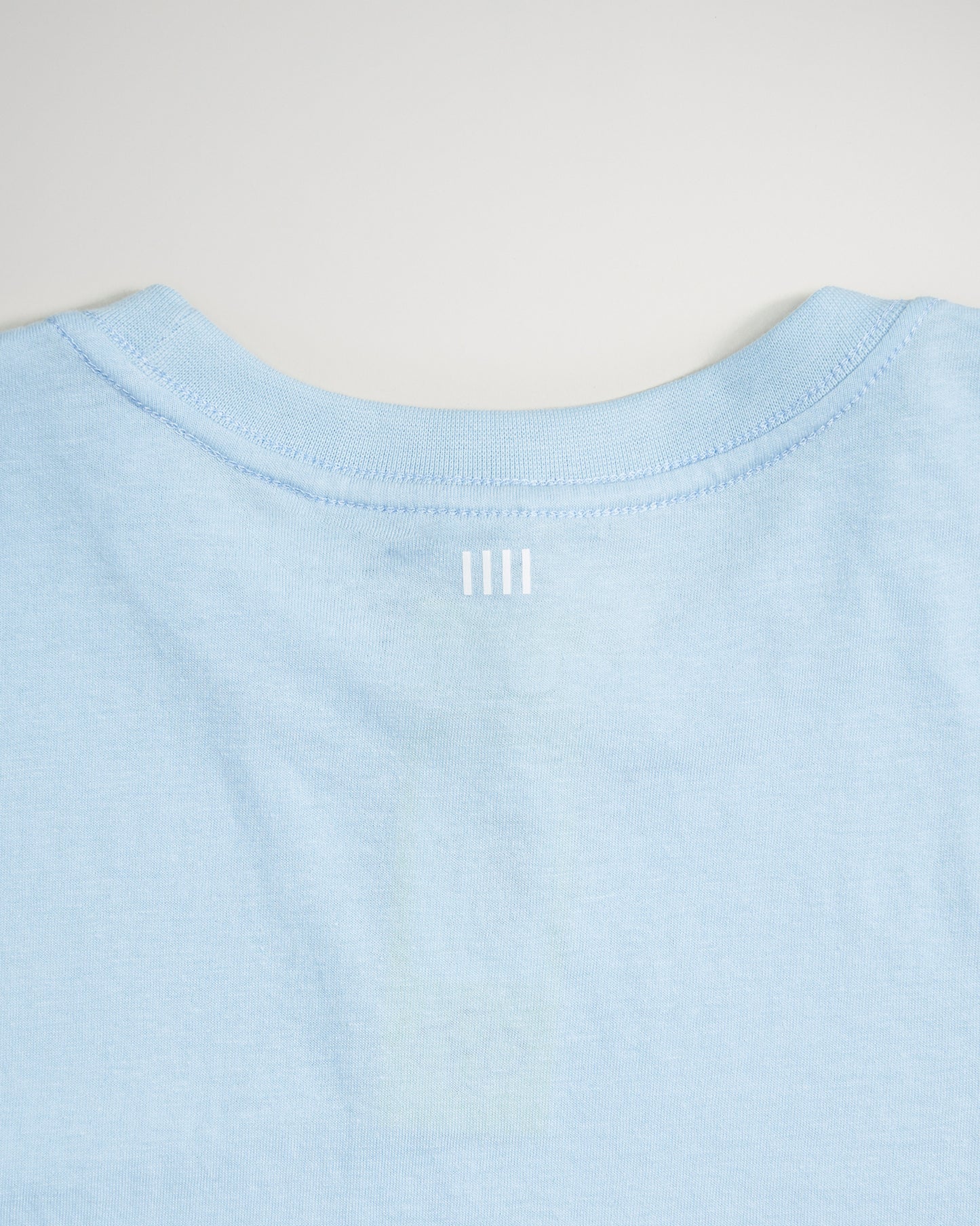 A light blue T-shirt featuring a simple modern design with a subtle white graphic at the neckline