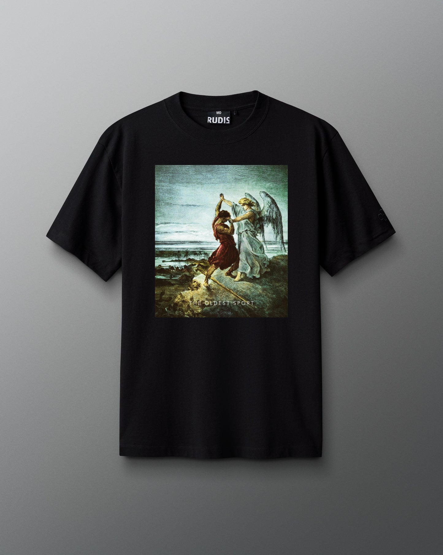 A black short-sleeve t-shirt is displayed against a gray background. Centered on the chest is a vivid artwork depicting Jacob wrestling an angel, set against a cloudy sky and landscape. Below the image, the words “THE OLDEST SPORT” appear in small white text. The shirt features a classic crewneck cut with the RUDIS logo printed inside the collar.