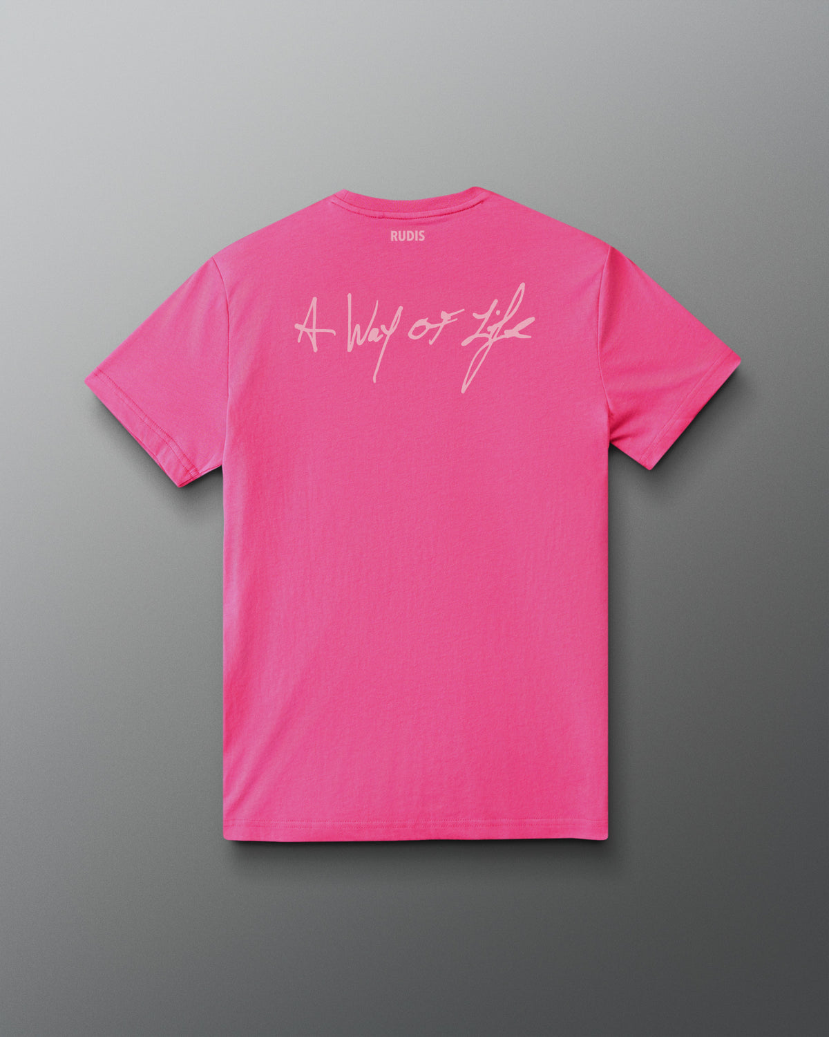 A bright pink short-sleeve t-shirt shown from the back, featuring a white cursive graphic that reads 'A Way of Life' across the upper back. The brand name 'RUDIS' is printed in small white letters inside the collar.