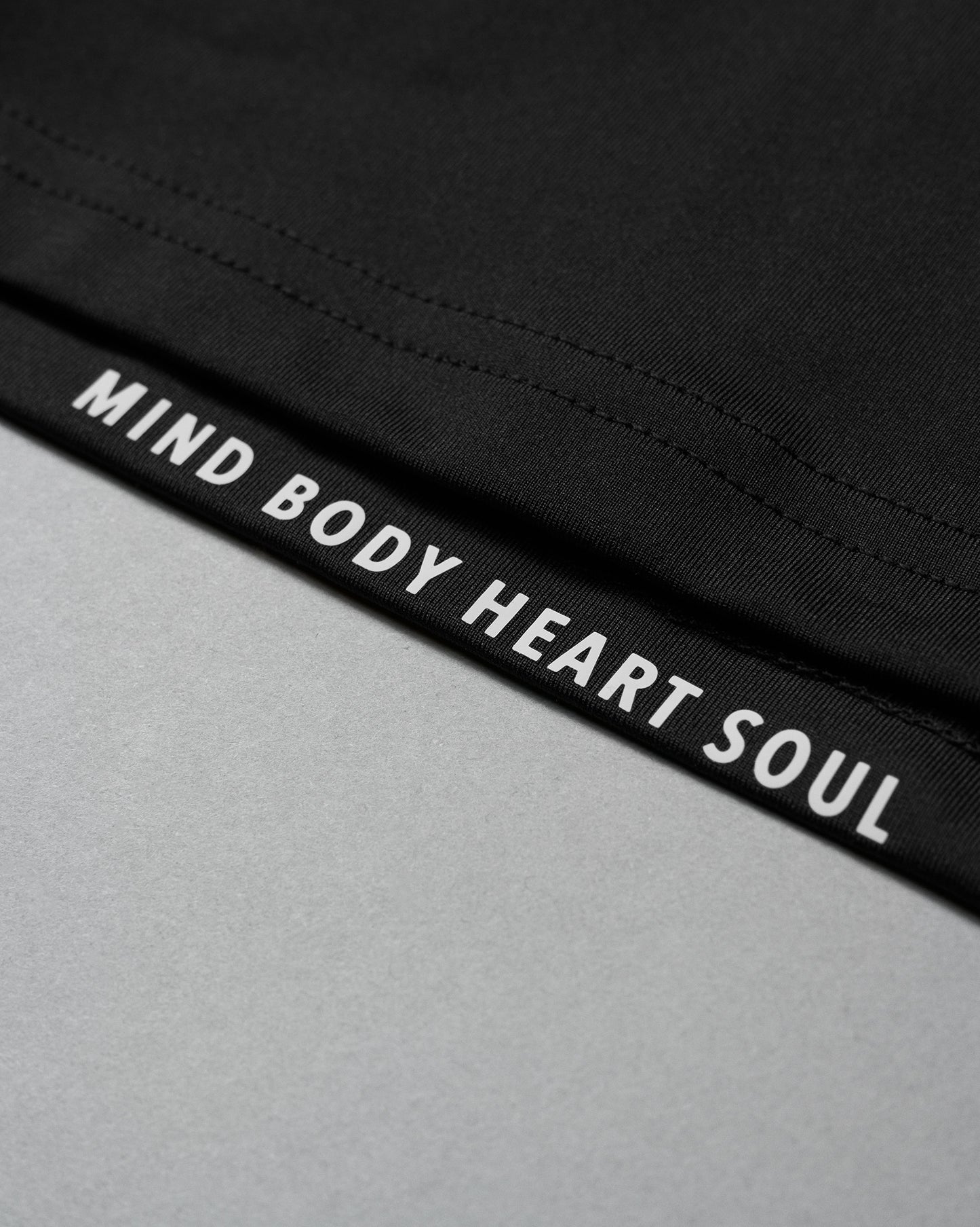 Black waistband with 'MIND BODY HEART SOUL' text on a gray background